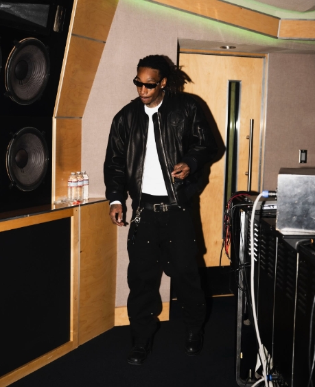 Wiz Khalifa wears a leather jacket, white thermal top, and sunglasses while walking through a recording studio in a post dated May 15, 2025. | Source: Facebook/Wiz Khalifa