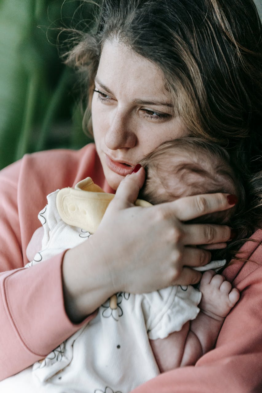 A mother lost in deep thought as she holds her baby | Source: Pexels