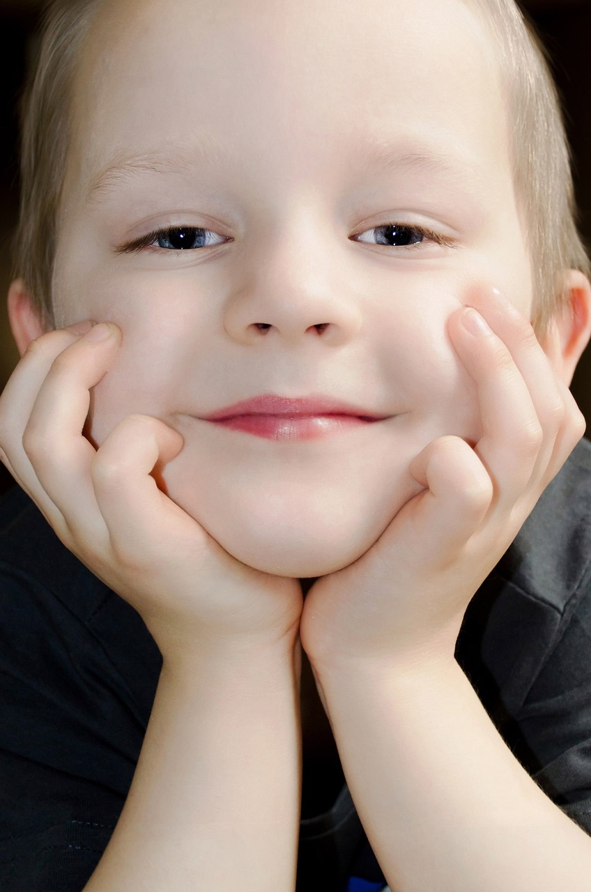 A cheerful little boy holding his face | Source: Pixabay