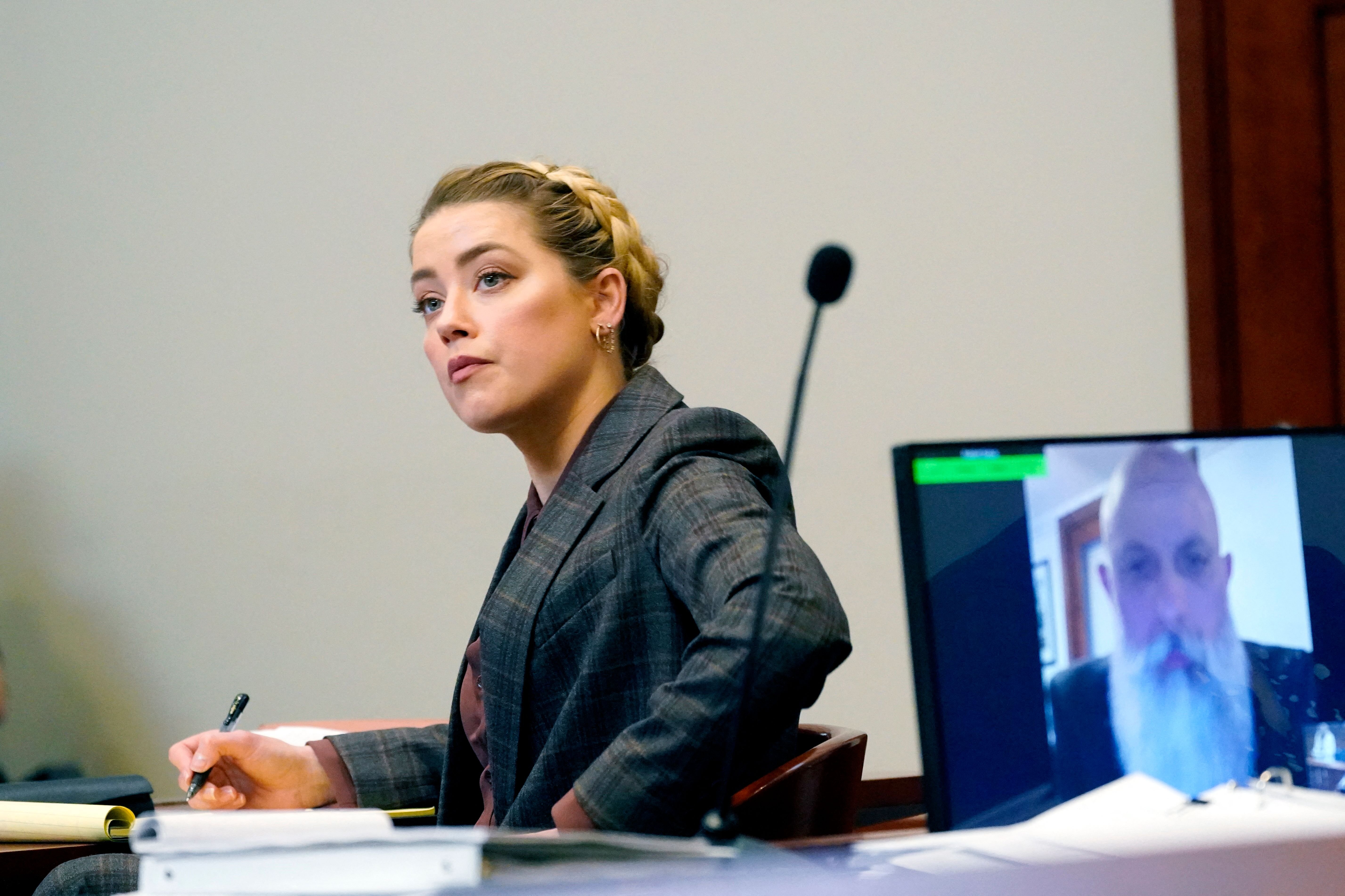 Amber Heard listening as Travis McGivern, a bodyguard for Johnny Depp, testifies remotely (R) in the courtroom at the Fairfax County Circuit Court on May 2, 2022 in Fairfax, Virginia. / Source: Getty Images