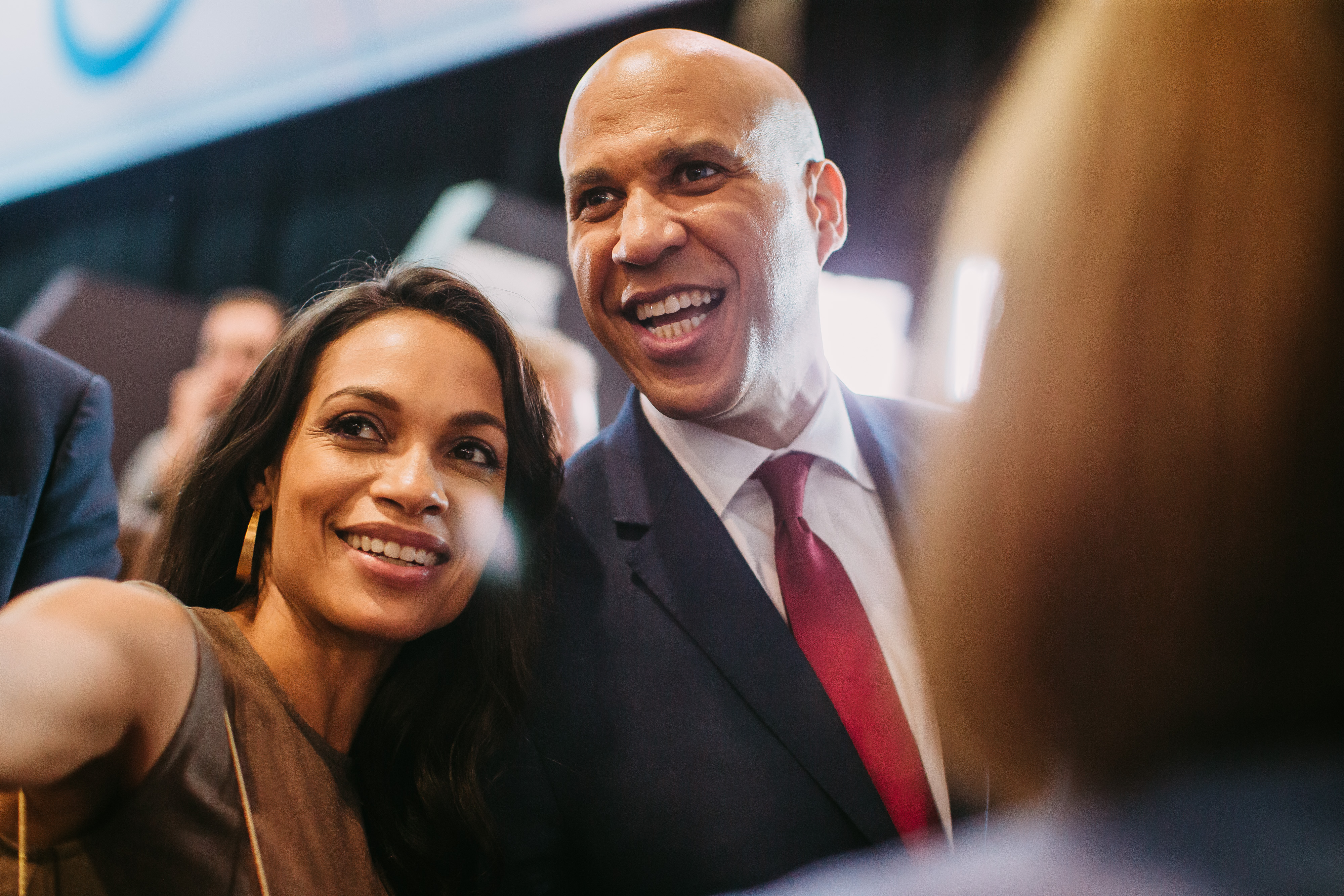 Senator Cory Booker and actress Rosario Dawson smile for a selfie in the spin room after the Democratic presidential debate in Westerville, Ohio, capturing a moment of connection amid the political spotlight.