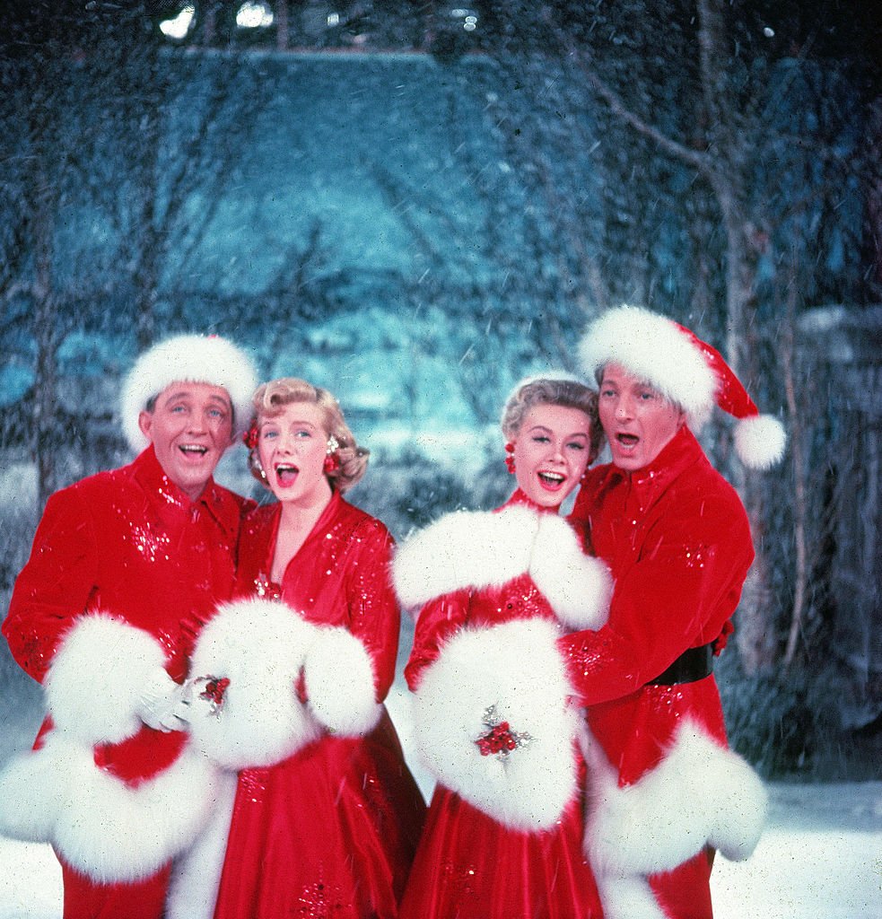 Bing Crosby, Rosemary Clooney, Vera-Ellen und Danny Kaye singen zusammen, während sie in pelzbesetzten roten Outfits gekleidet sind und vor einem stehen Stage Backrop, in einer Szene aus dem Film 'White Christmas' | Quelle: Getty Images