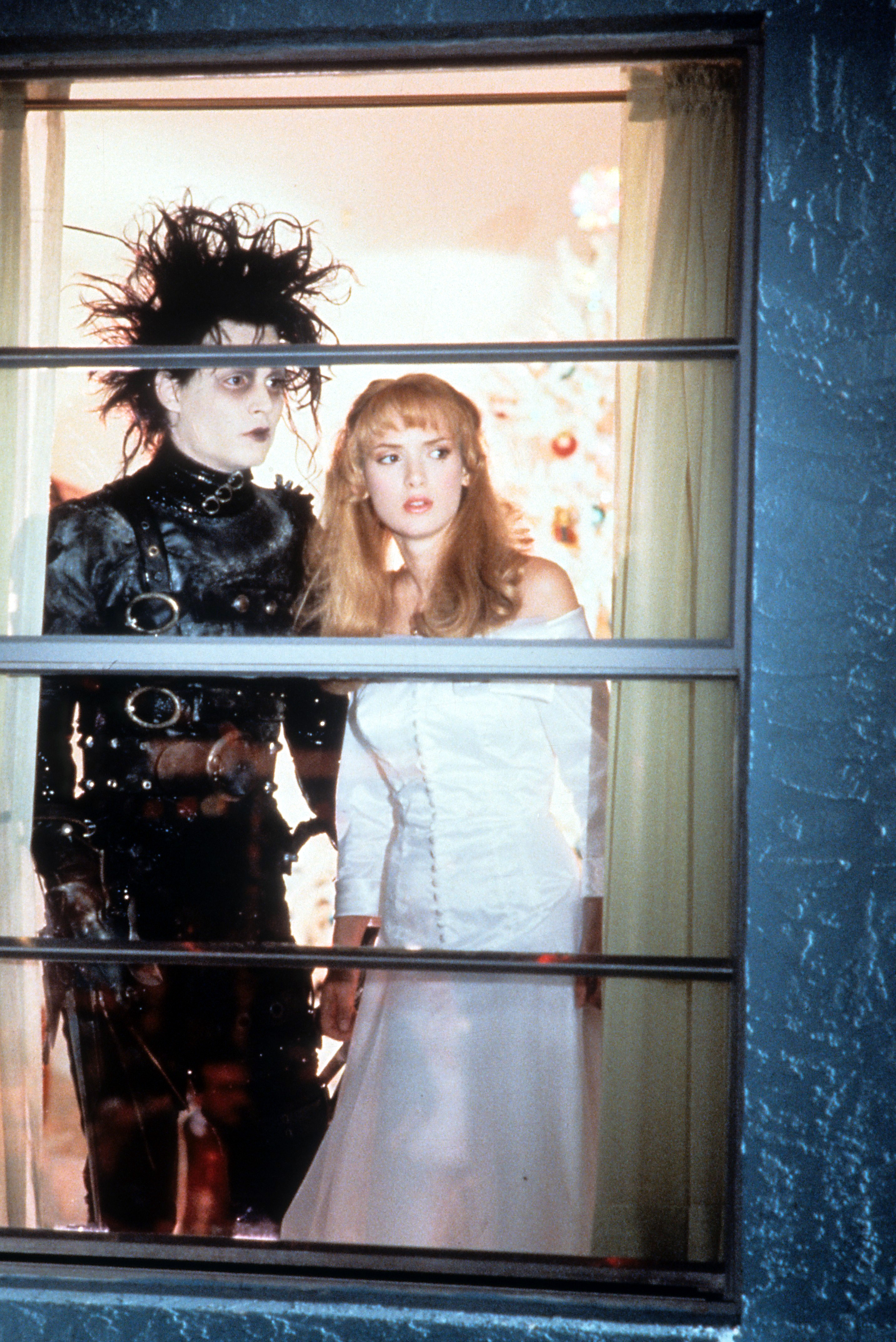 Johnny Depp y la actriz Winona Ryder fotografiados mirando por la ventana en una escena de la película "Edward Scissorhands", el 1 de enero de 1990. | Foto: Getty Images