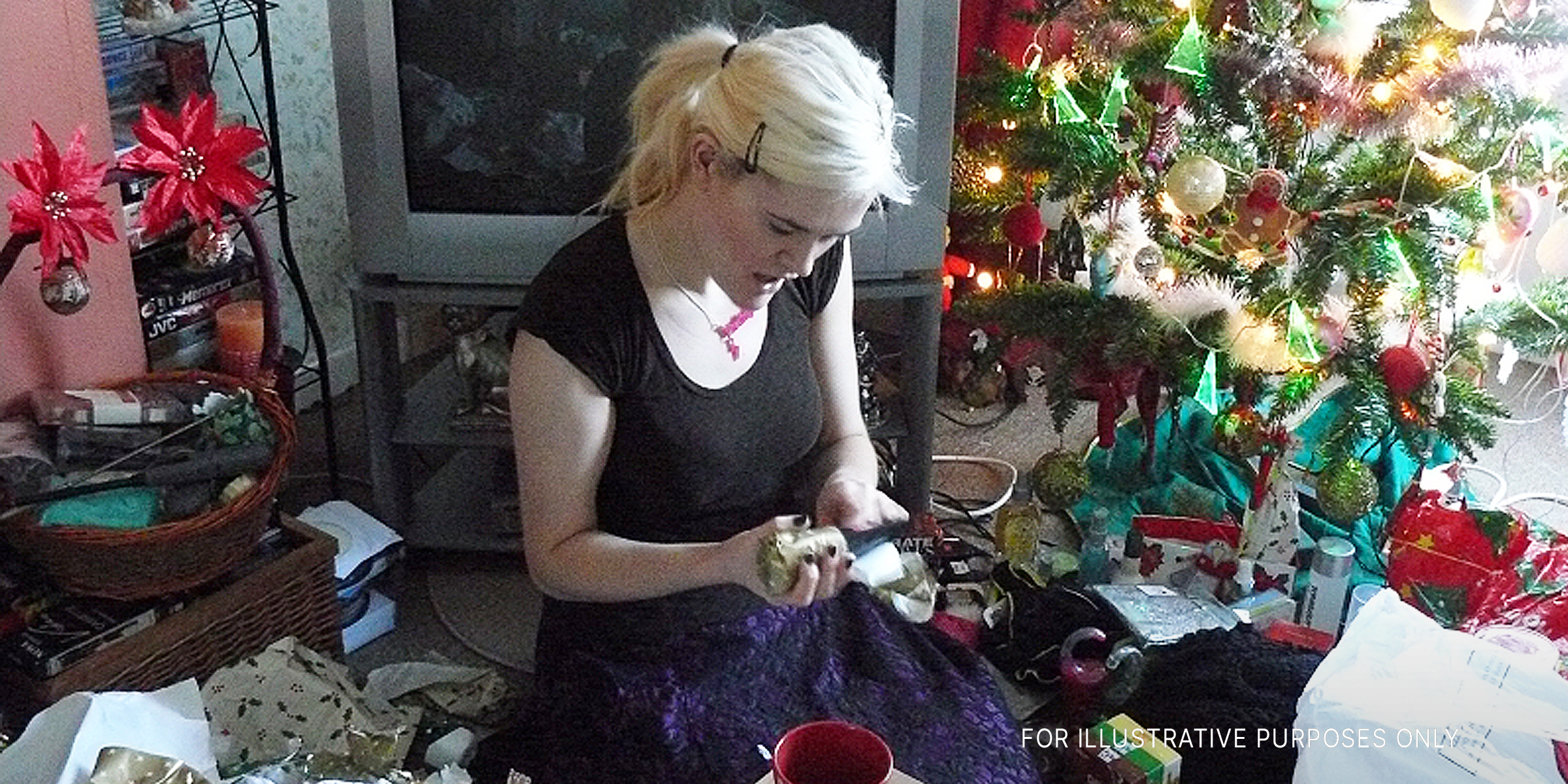 A young woman unwraps a Christmas present | Source: flickr.com/flem007_uk/CC BY-ND 2.0
