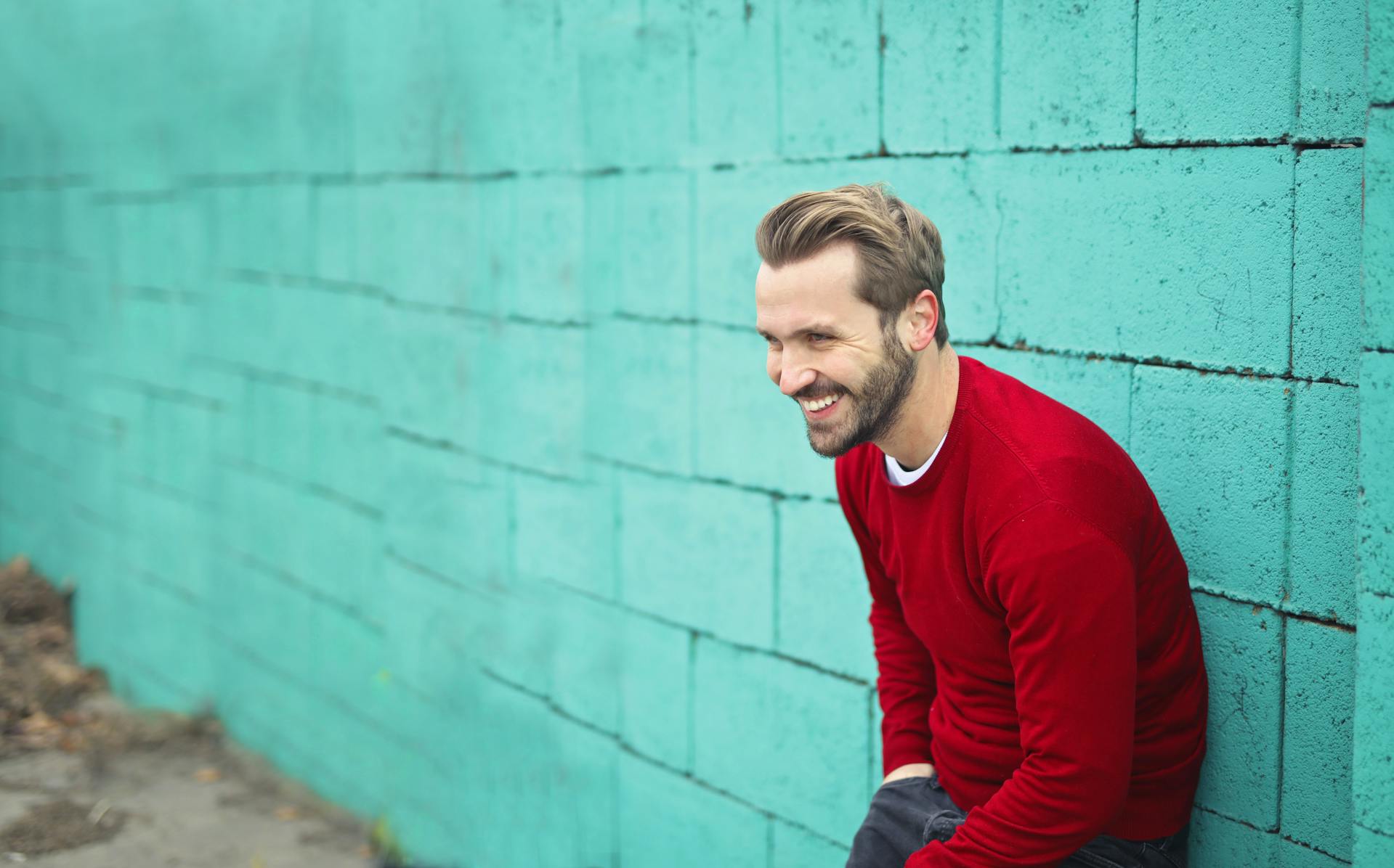 A smiling man leaning against a wall | Source: Pexels