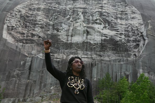 Lahahuia Hanks holds up a fist in front of the Confederate carving at Stone Mountain Park during a Black Lives Matter protest on June 16, 2020 in Stone Mountain, Georgia. | Photo: Getty Images