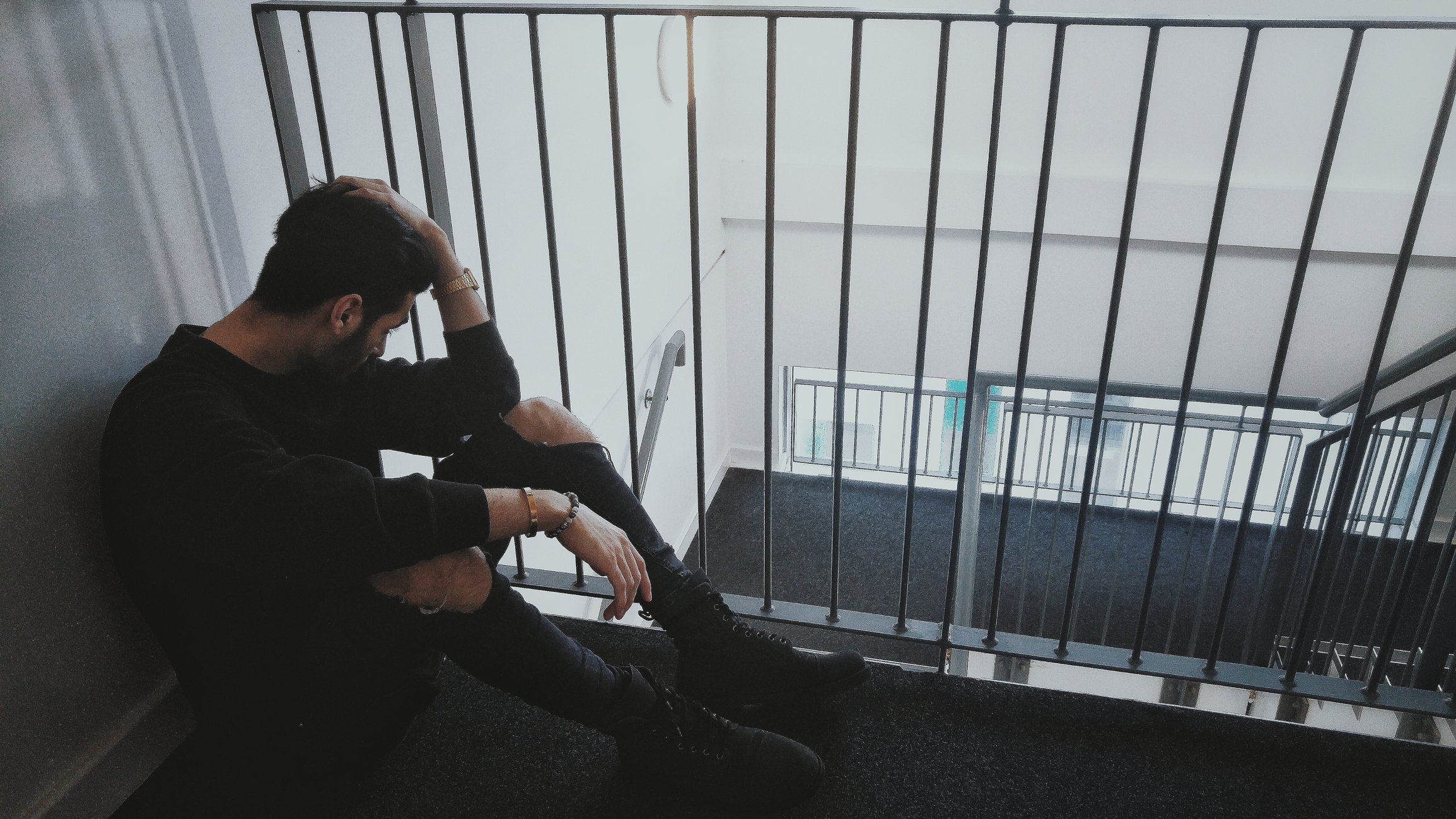 Depressiver Mann, der am Geländer im Gebäude sitzt. I Quelle: Getty Images