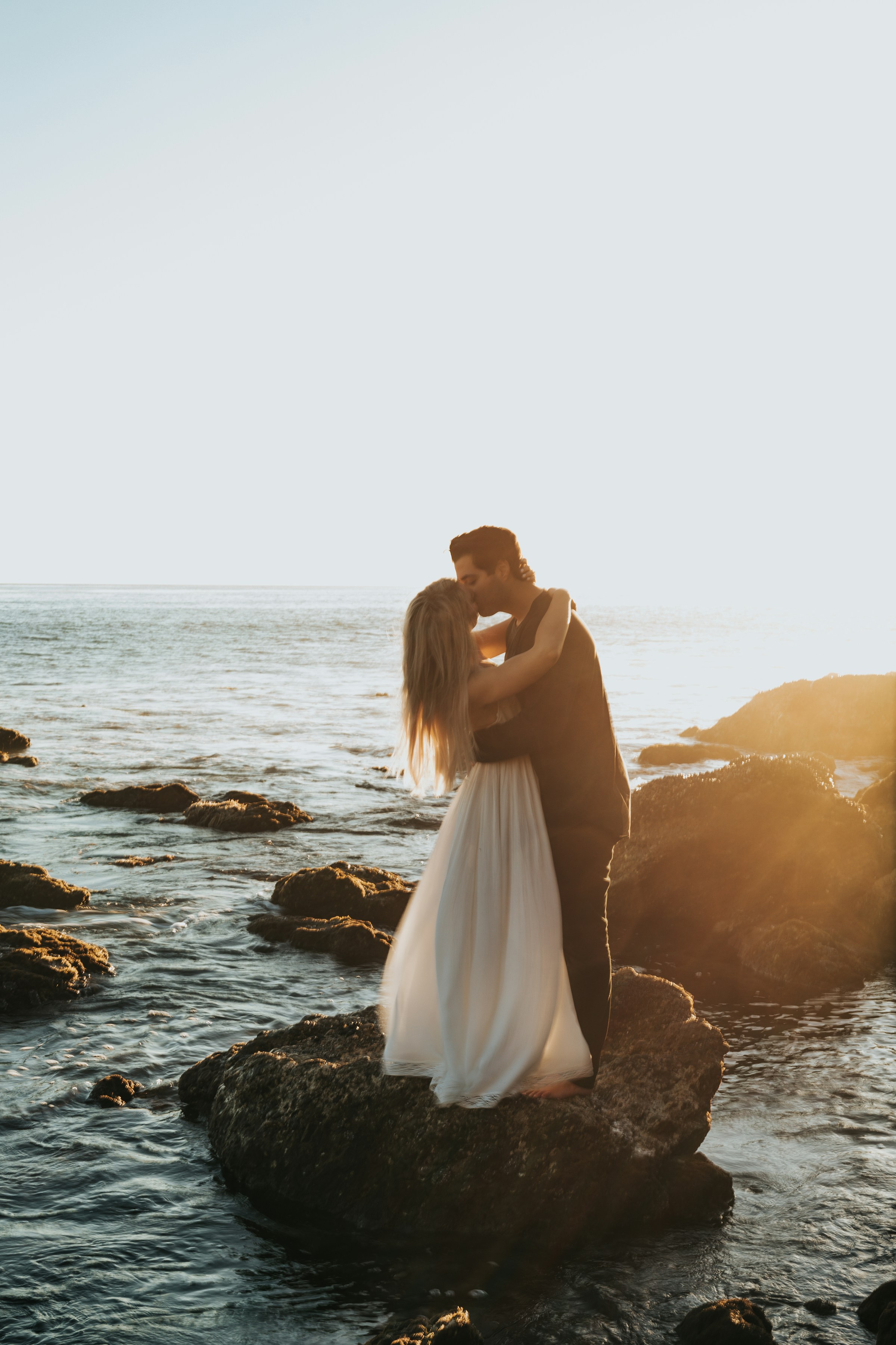 A couple kissing while standing on top of a rock at a beach | Source: Unsplash