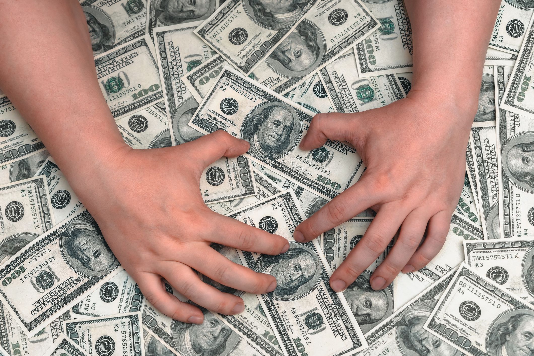 Zwei Hände halten einen großen Haufen Dollarscheine. | Quelle: Shutterstock