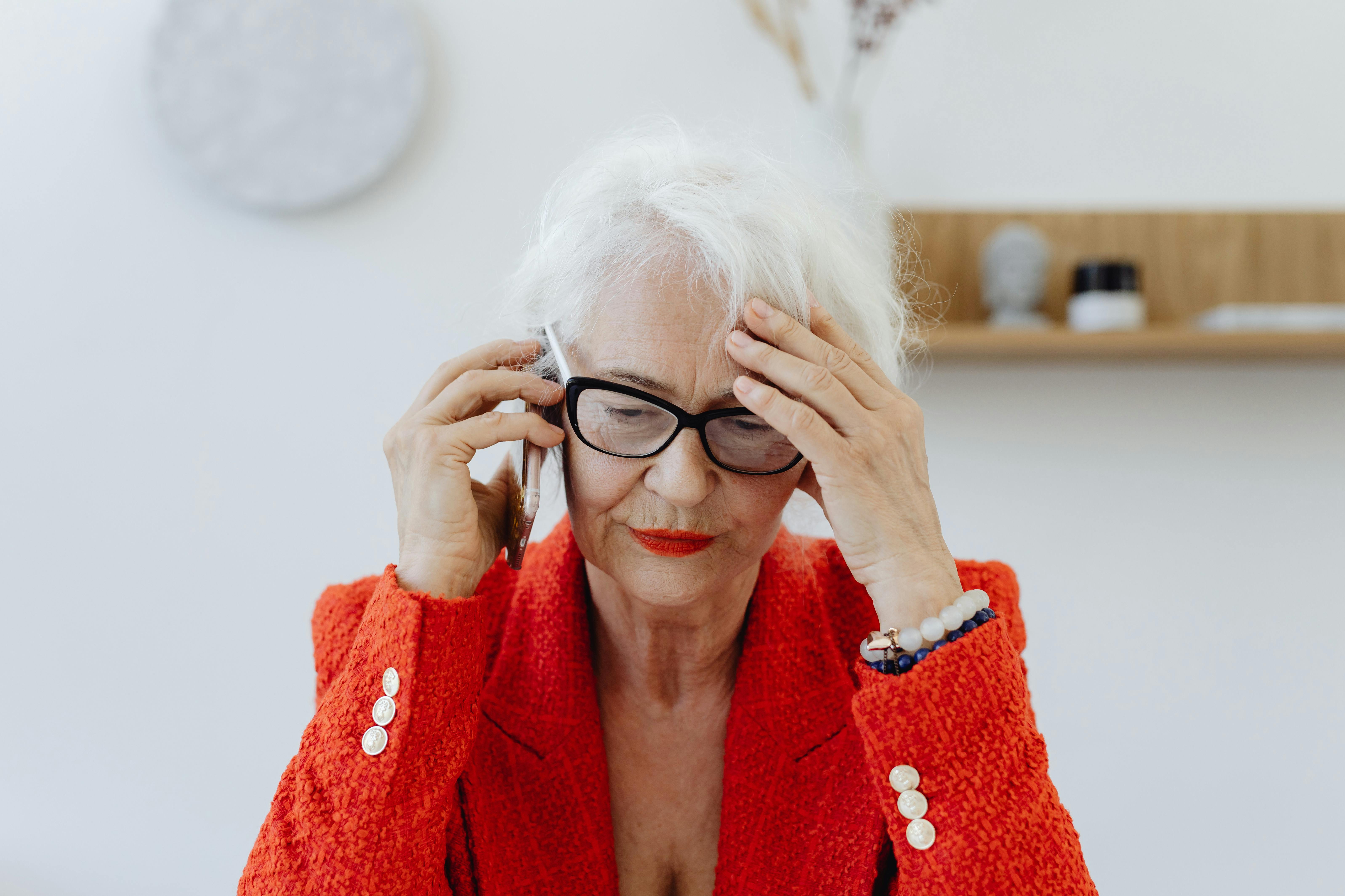 A relaxed woman in a red coat holding a phone with one hand | Source: Pexels