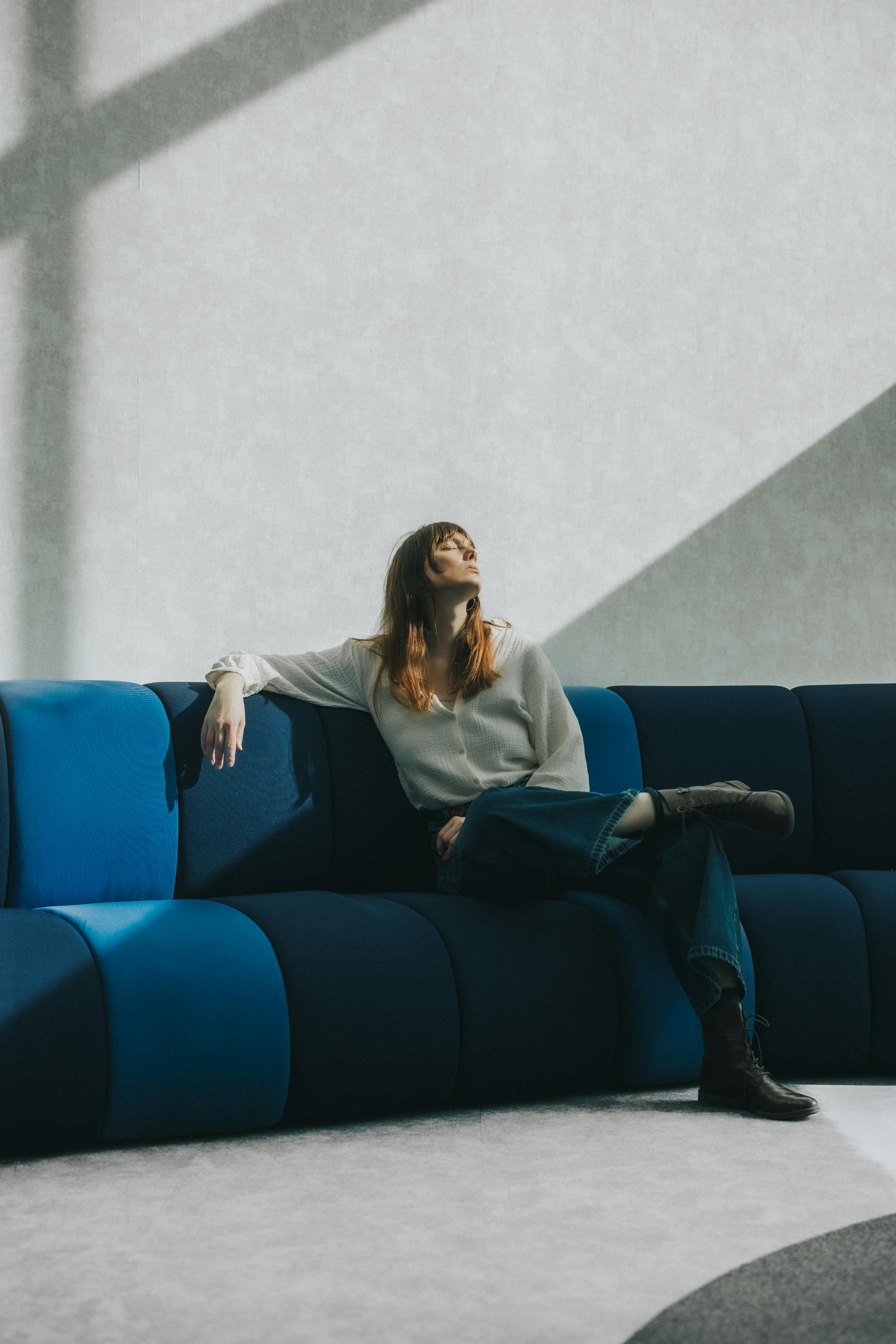 A woman sitting on a sofa, deep in thought | Source: Pexels