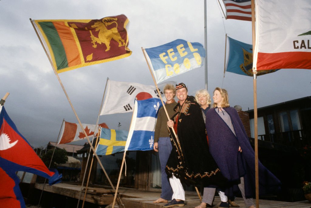 Porträt des amerikanischen Fernsehschauspielers Larry Hagman (zweiter von rechts) und seiner Familie, die mit einer Reihe von Flaggen in ihrem Haus am Strand in Malibu, Kalifornien, Januar 1980 posieren. | Quelle: Getty Images