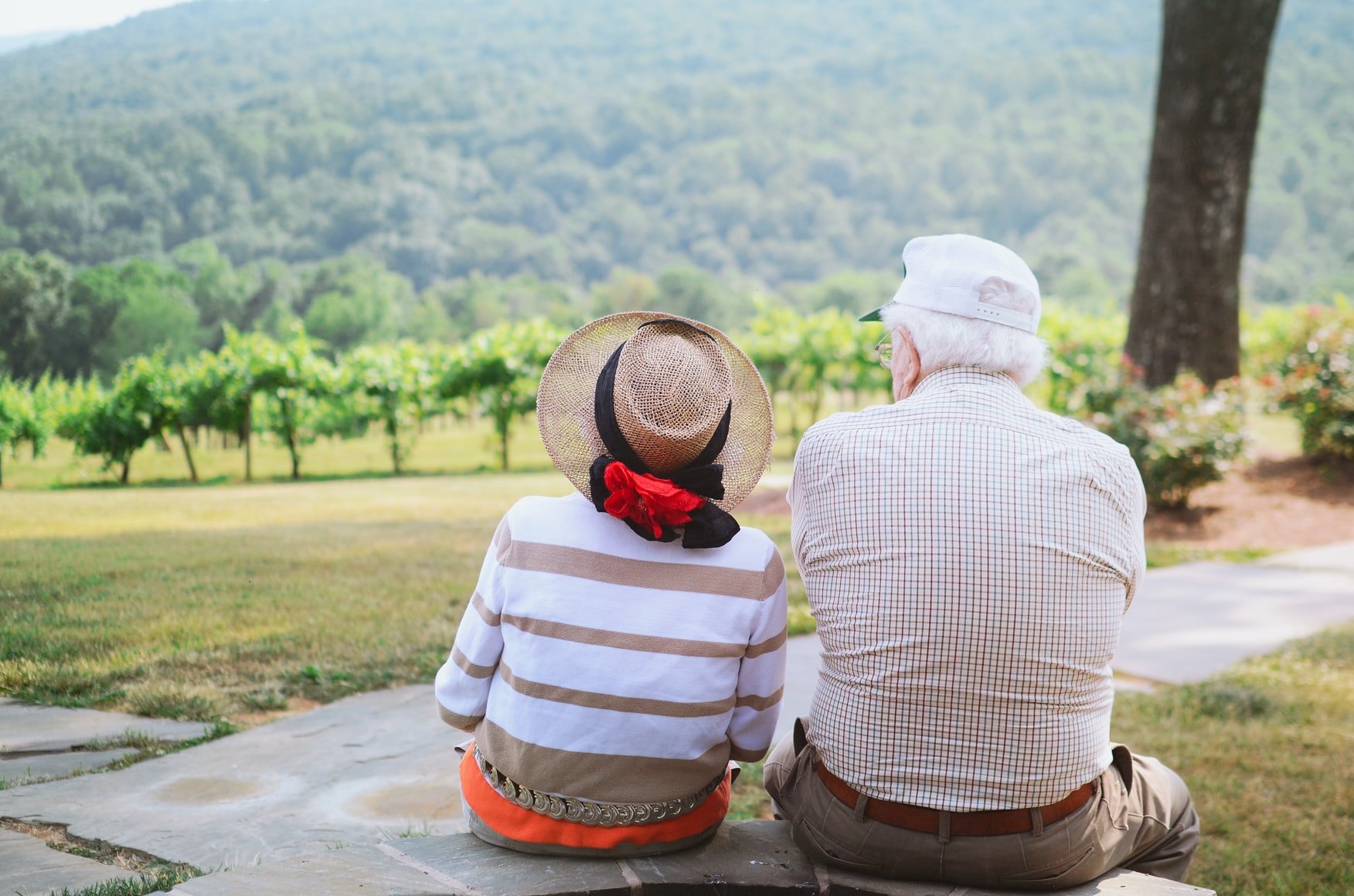 Ein älteres Ehepaar sitzt auf einer grünen Wiese. | Quelle: Unsplash