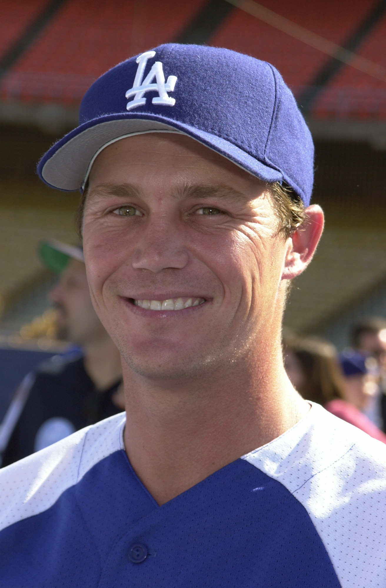 Brian Krause is seen at a celebrity baseball game in the early 2000s, smiling in a Los Angeles Dodgers uniform and cap. The bright sunlight and stadium setting capture the casual, cheerful energy of the event, showing a different side of the actor known for his role on “Charmed.”