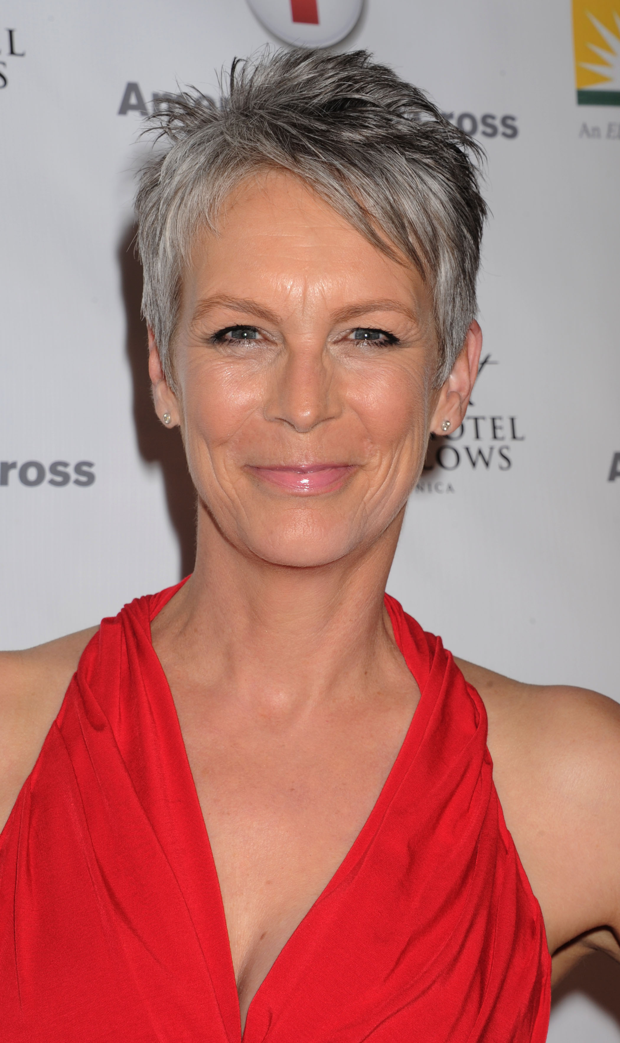 Jamie Lee Curtis turns heads in a bold, draped red gown at the American Red Cross Red Tie Affair, her radiant smile and textured silver pixie cut perfectly capturing the event’s spirited elegance.