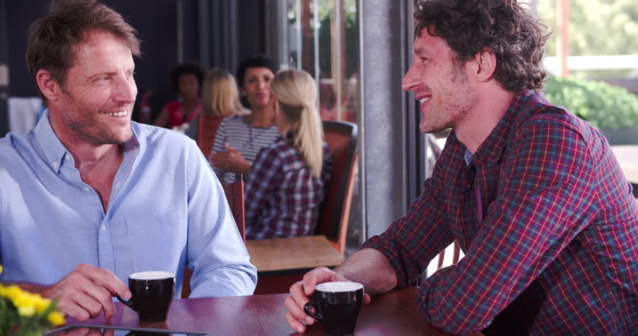 Two mature mature male friends sitting, and talking over coffee | Photo: Shutterstock