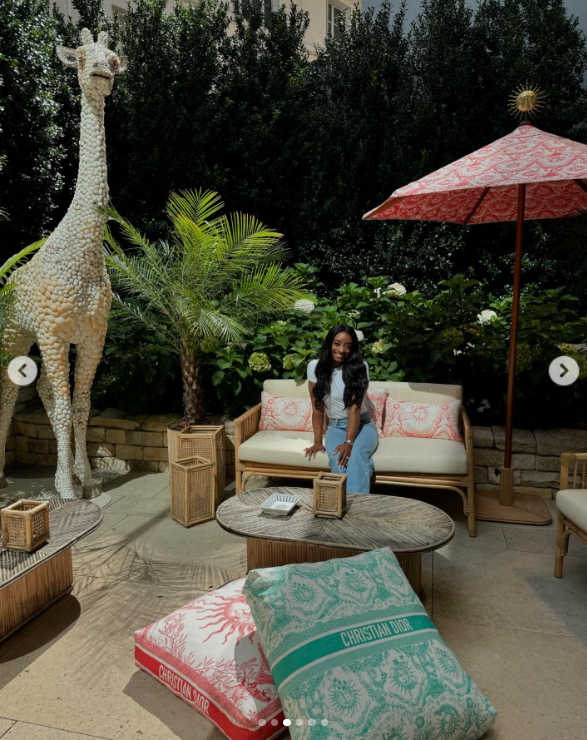 Simone Biles lounges on a white couch with two Christian Dior square pillows while in Paris, France, posted in August 2024 | Source: Instagram.com/simonebiles