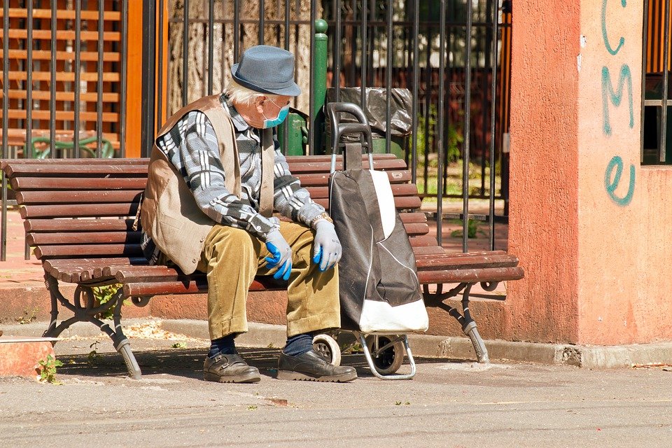 Abuelo con mascarilla y guantes sentado en una silla en la vía pública. | Foto: Pixabay