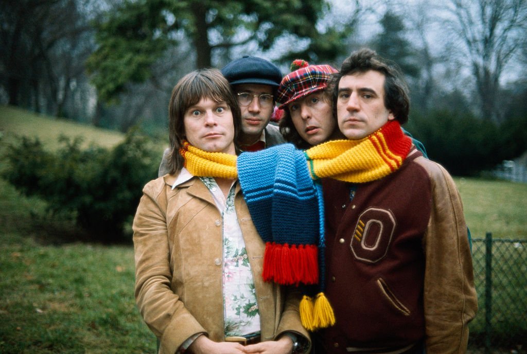 Des comédiens de la troupe britannique Monty Python posent avec un grand foulard autour du cou lors d'une visite à Paris. (G-D) : Terry Gilliam, le musicien et second rôle Neil Innes, Eric Idle et Terry Jones. | Photo : Getty Images Des comédiens de la troupe britannique Monty Python posent avec un grand foulard autour du cou lors d'une visite à Paris. (G-D) : Terry Gilliam, le musicien et second rôle Neil Innes, Eric Idle et Terry Jones. | Photo : Getty Images