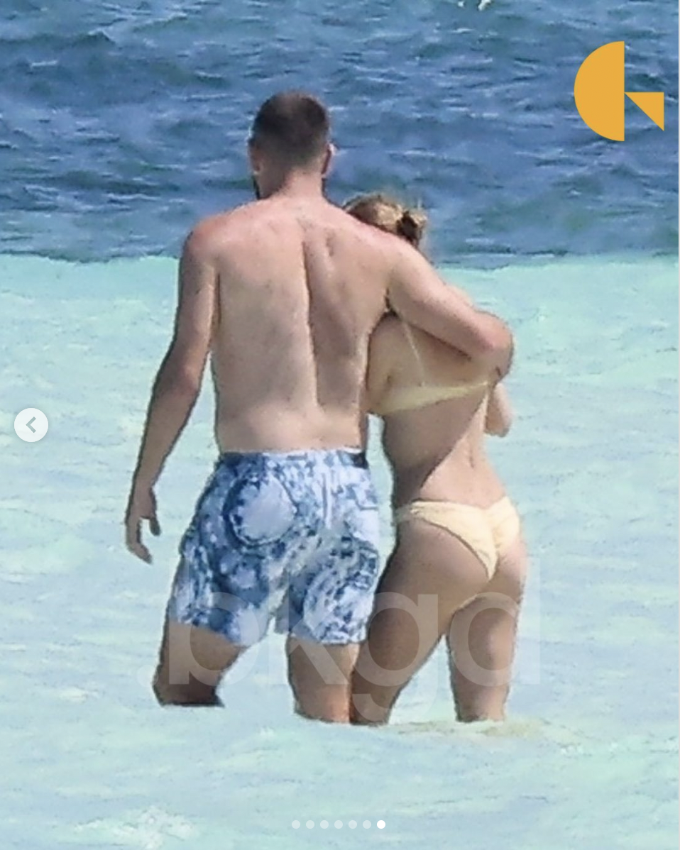 Travis Kelce and Taylor Swift walking towards the water on a beach in the Bahamas on March 21, 2024 | Source: Instagram/backgrid_usa