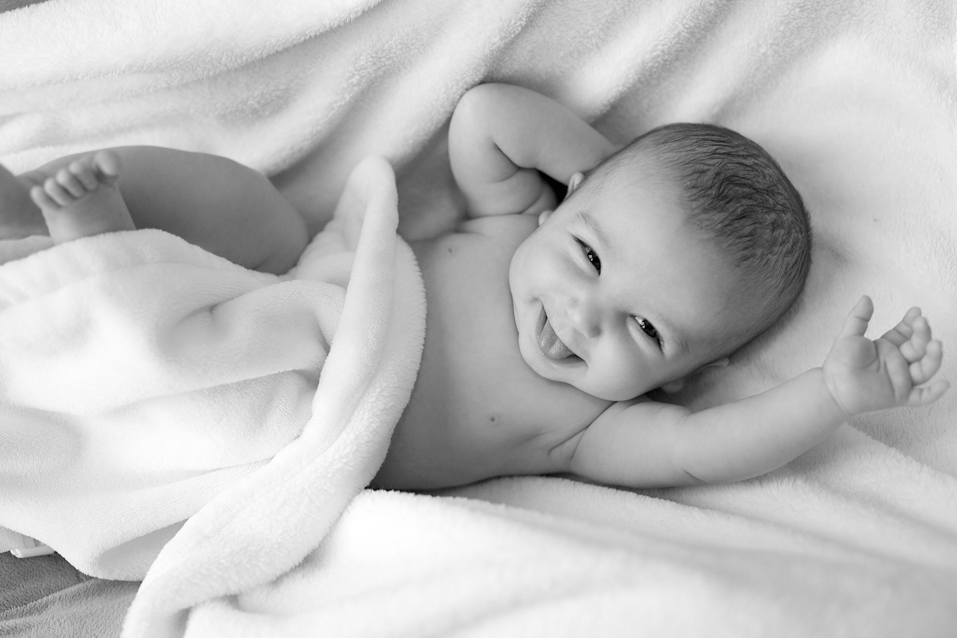 A baby smiling in bed. | Source: Pixabay 
