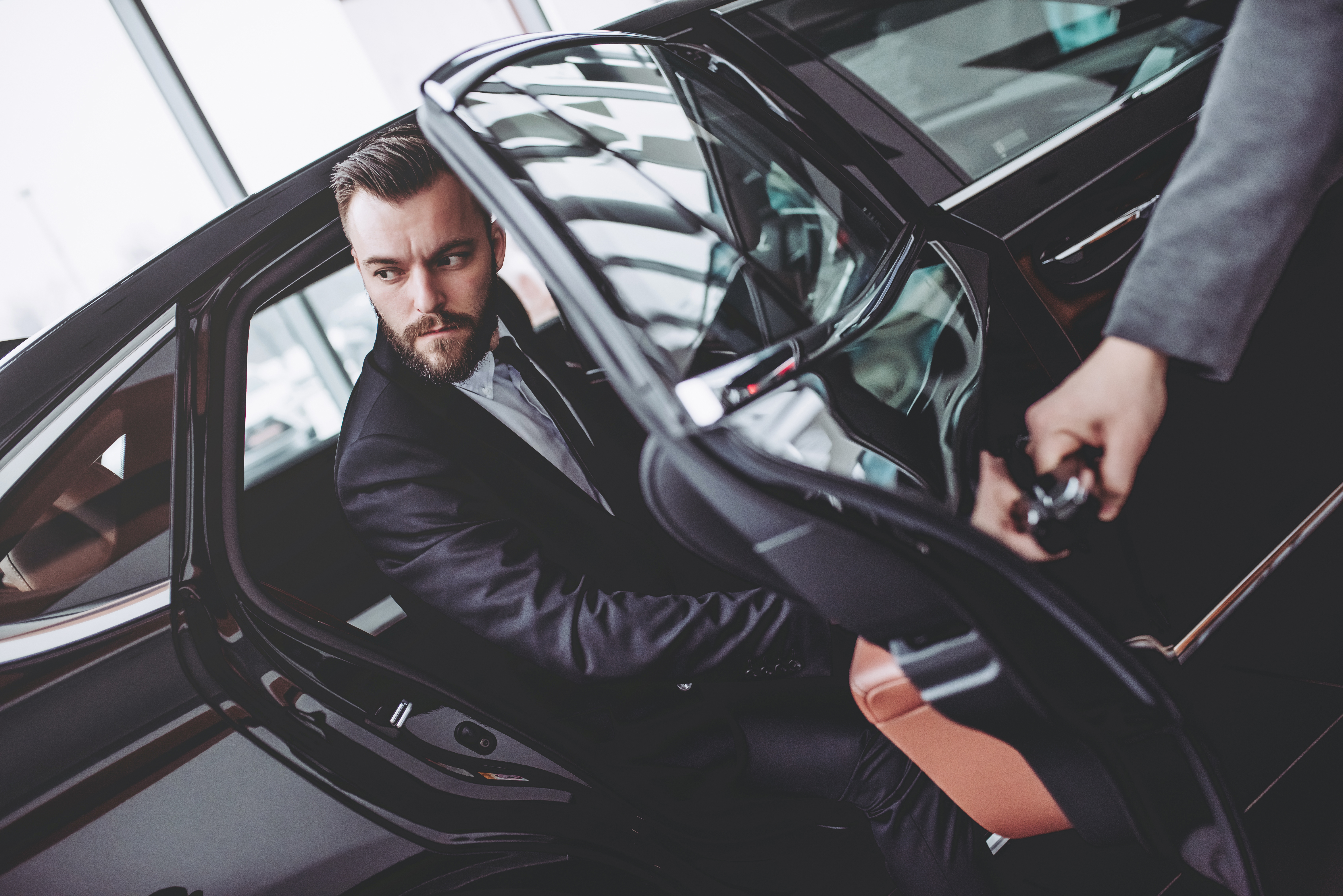 Serious bearded man in suit is coming out while driver is opening door. | Source: Shutterstock