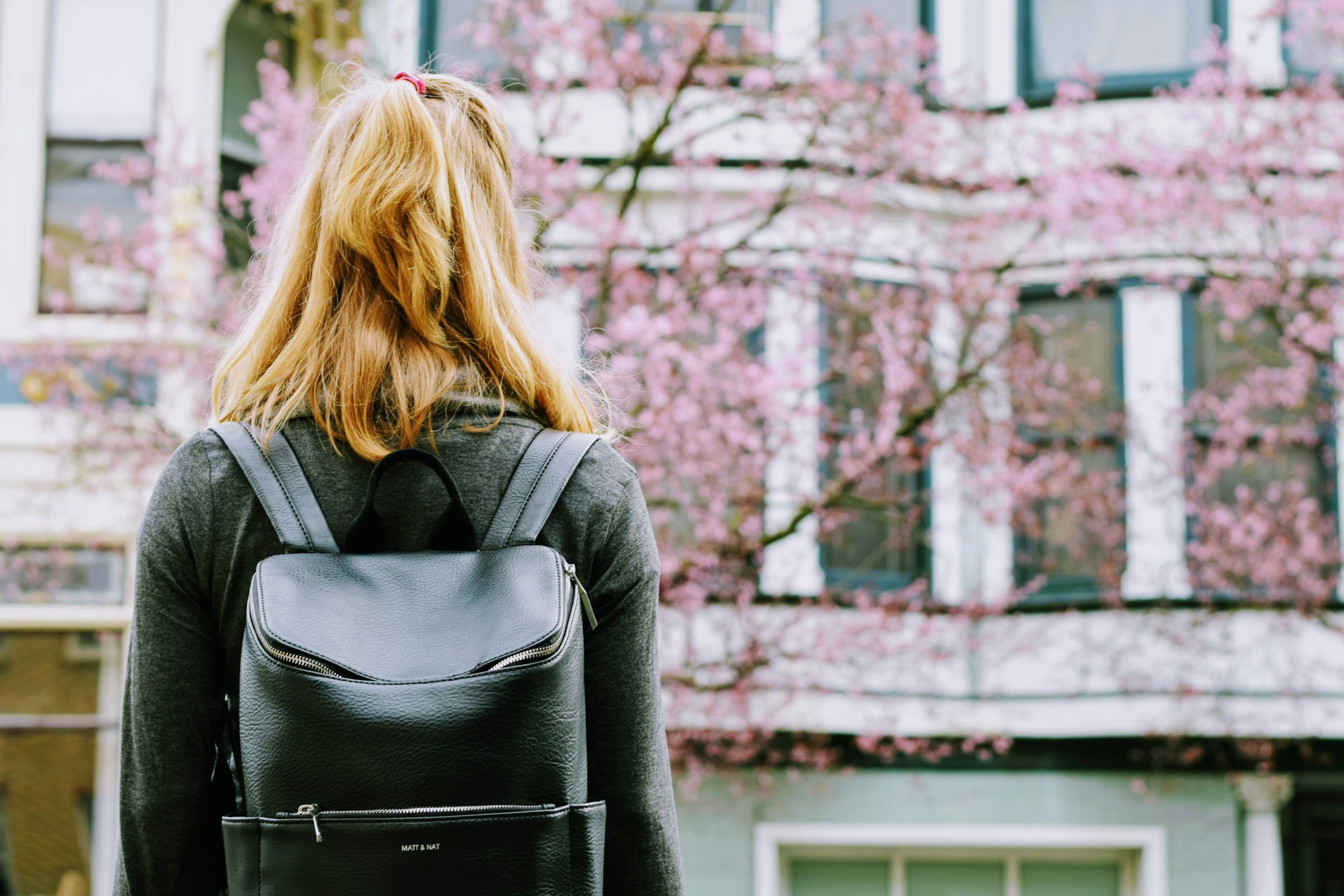 A back view of a young woman with a backpack standing in front of a building | Source: Unsplash