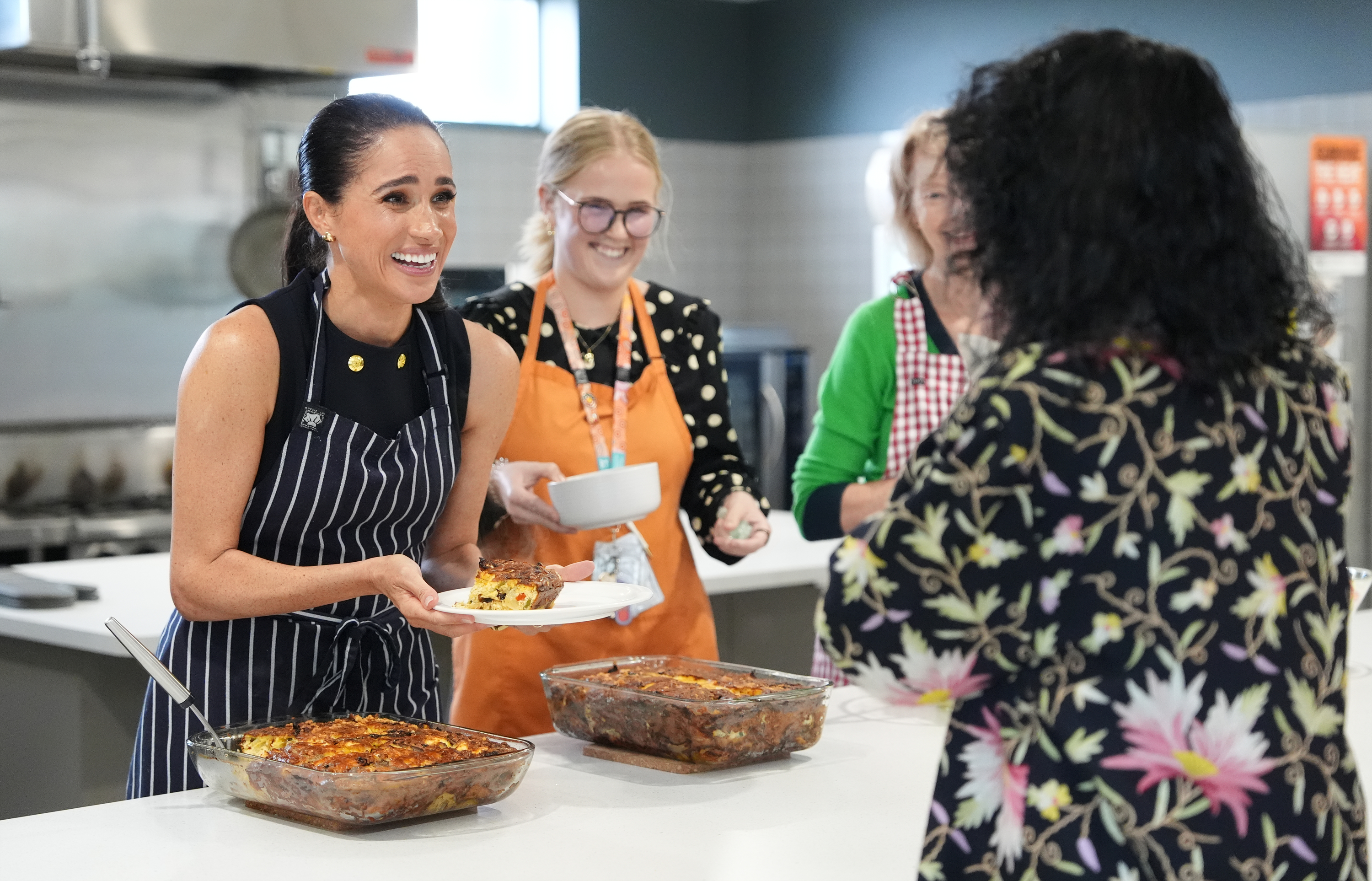 Meghan, Duchess of Sussex and staff at McAuley Community Services for Women, a women's homeless and family violence shelter, serves lunch to a resident on 14 April 2026 in the Footscray suburb of Melbourne, Australia. | Source: Getty Images