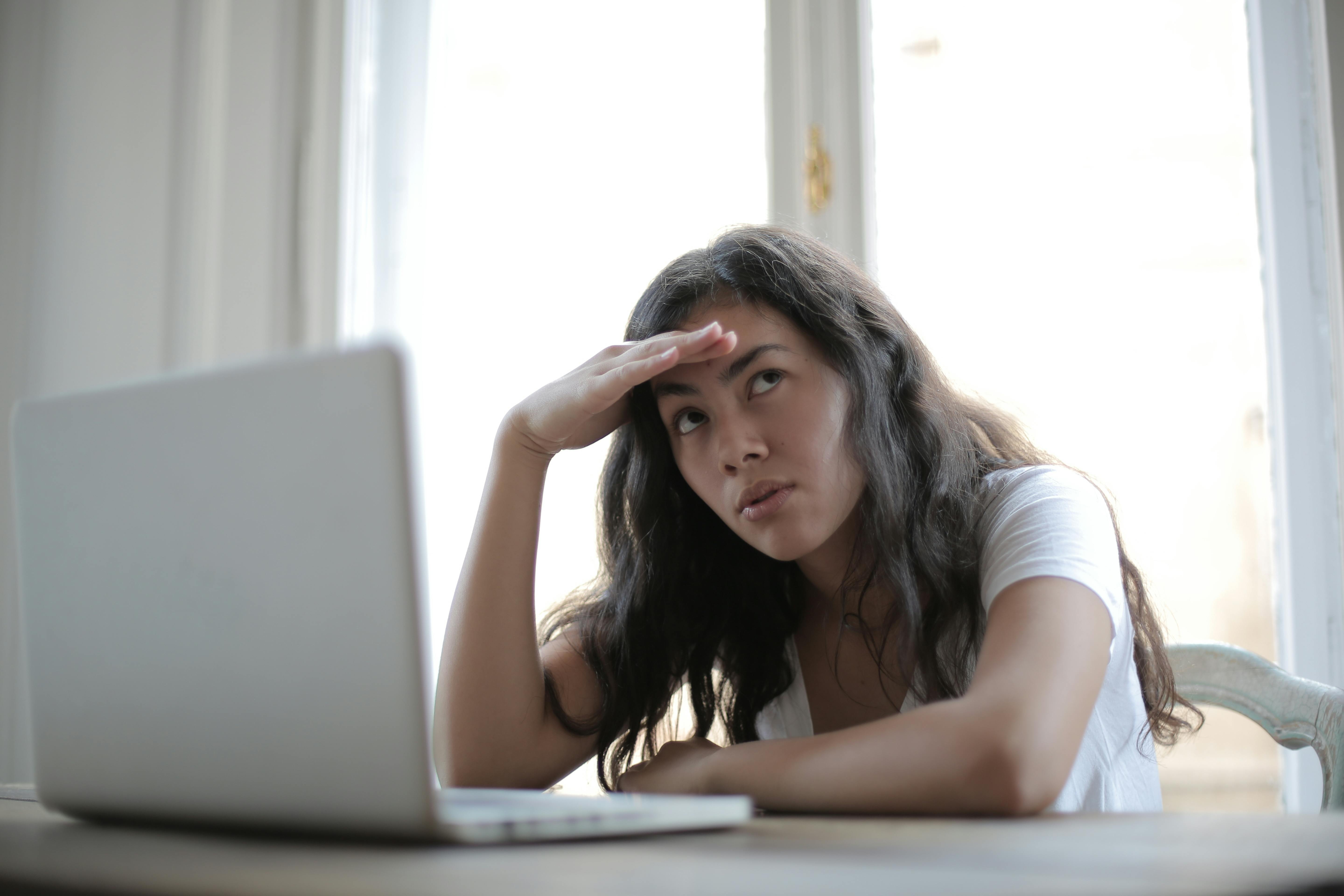 A woman sitting in front of a computer contemplating something | Source: Pexels