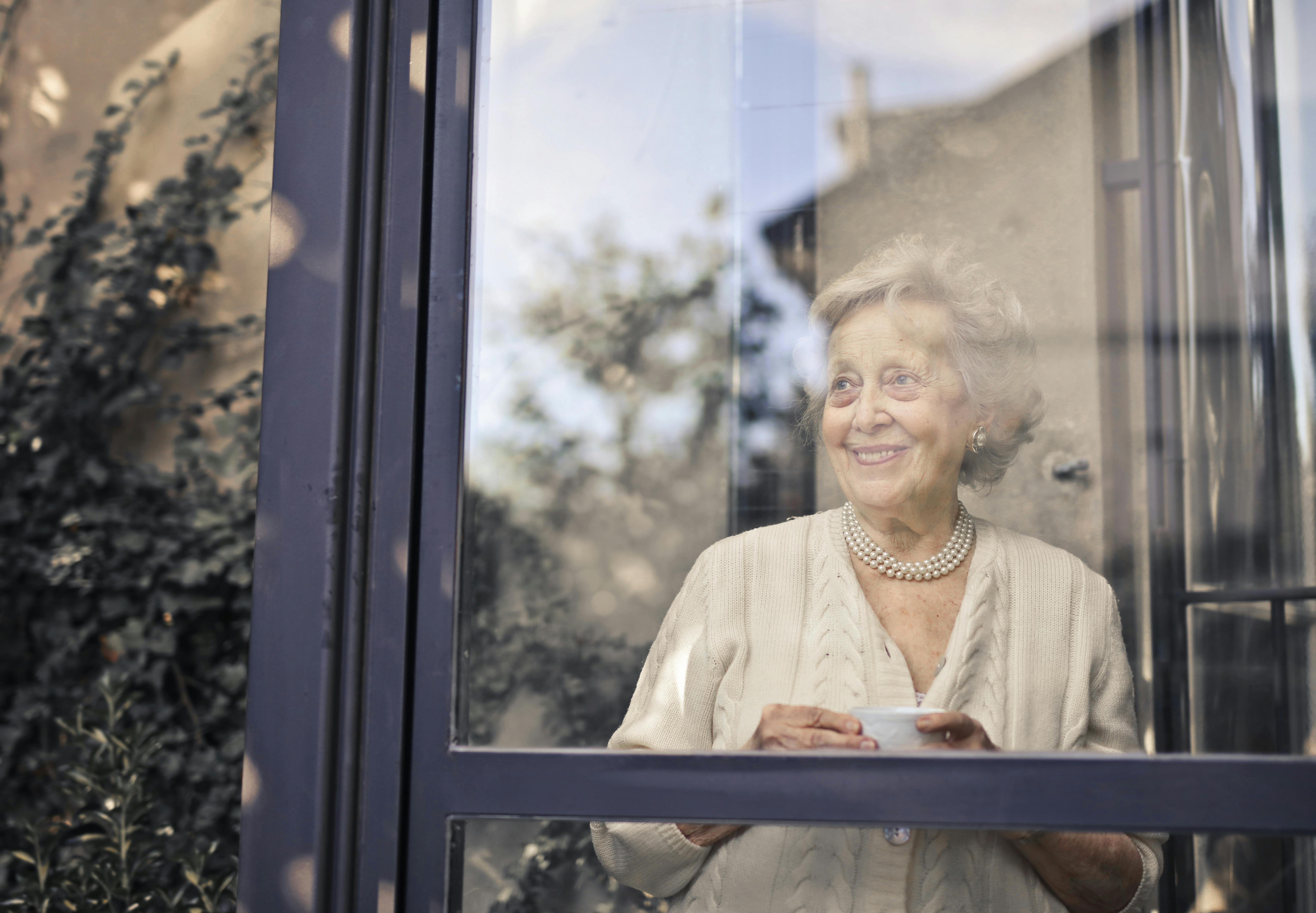 An elderly woman standing by the window | Source: Pexels