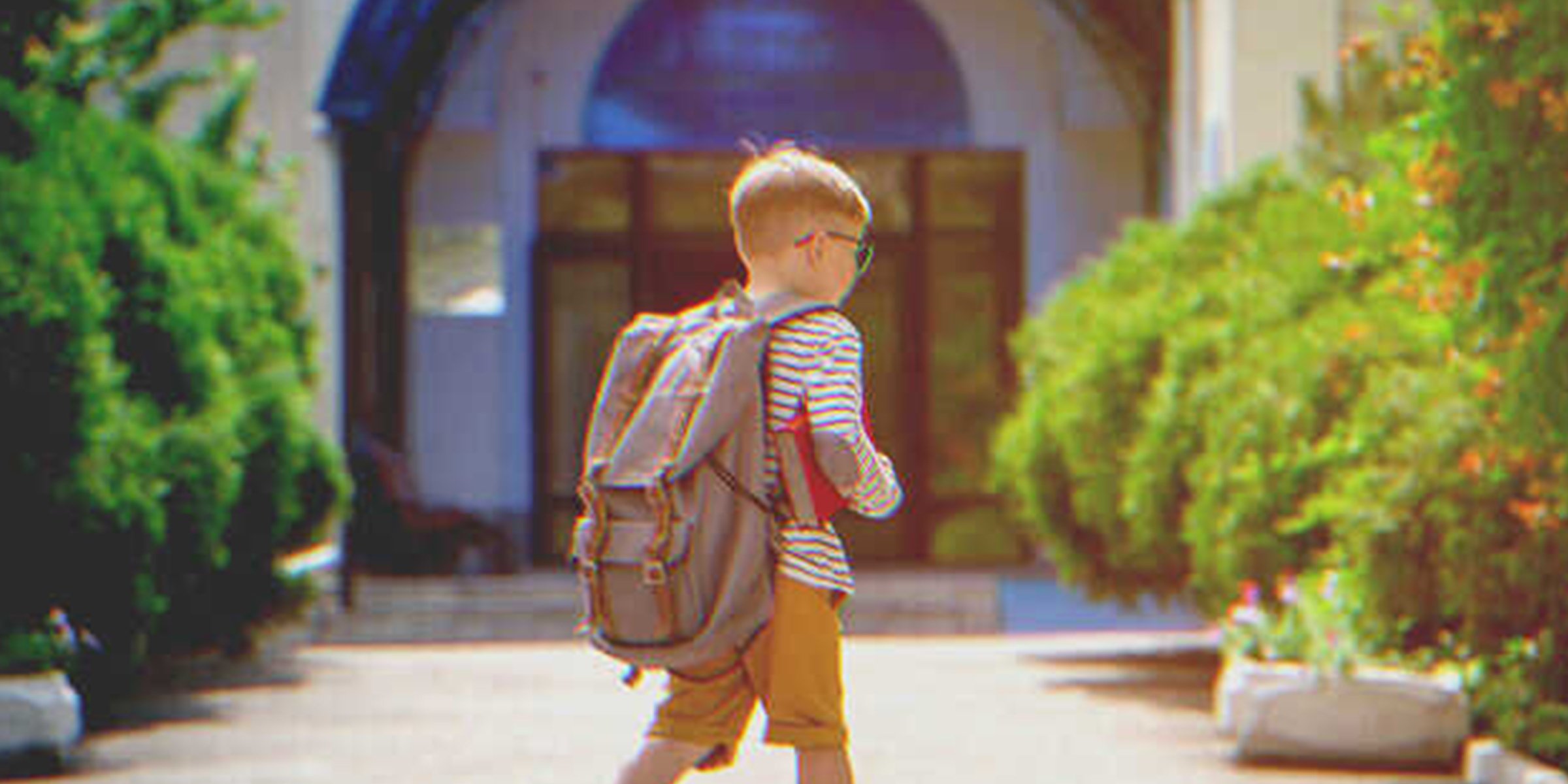 A kid with a backpack walking to a building | Source: Shutterstock