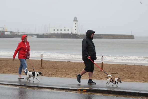 Des gens promènent leur chien sur le front de mer venteux de Scarborough, dans le North Yorkshire. | Photo : Getty Images Des gens promènent leur chien sur le front de mer venteux de Scarborough, dans le North Yorkshire. | Photo : Getty Images