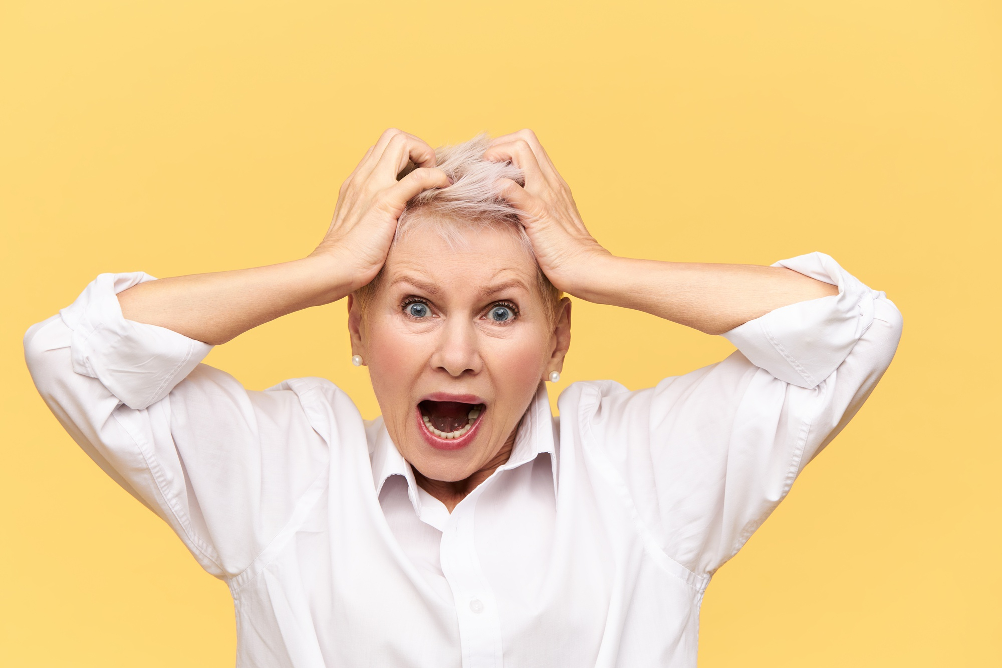 An angry middle-aged woman with her hands on her head | Source: Freepik