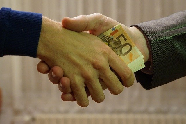 Two men shake hands with money in their hands | Photo: Pixabay