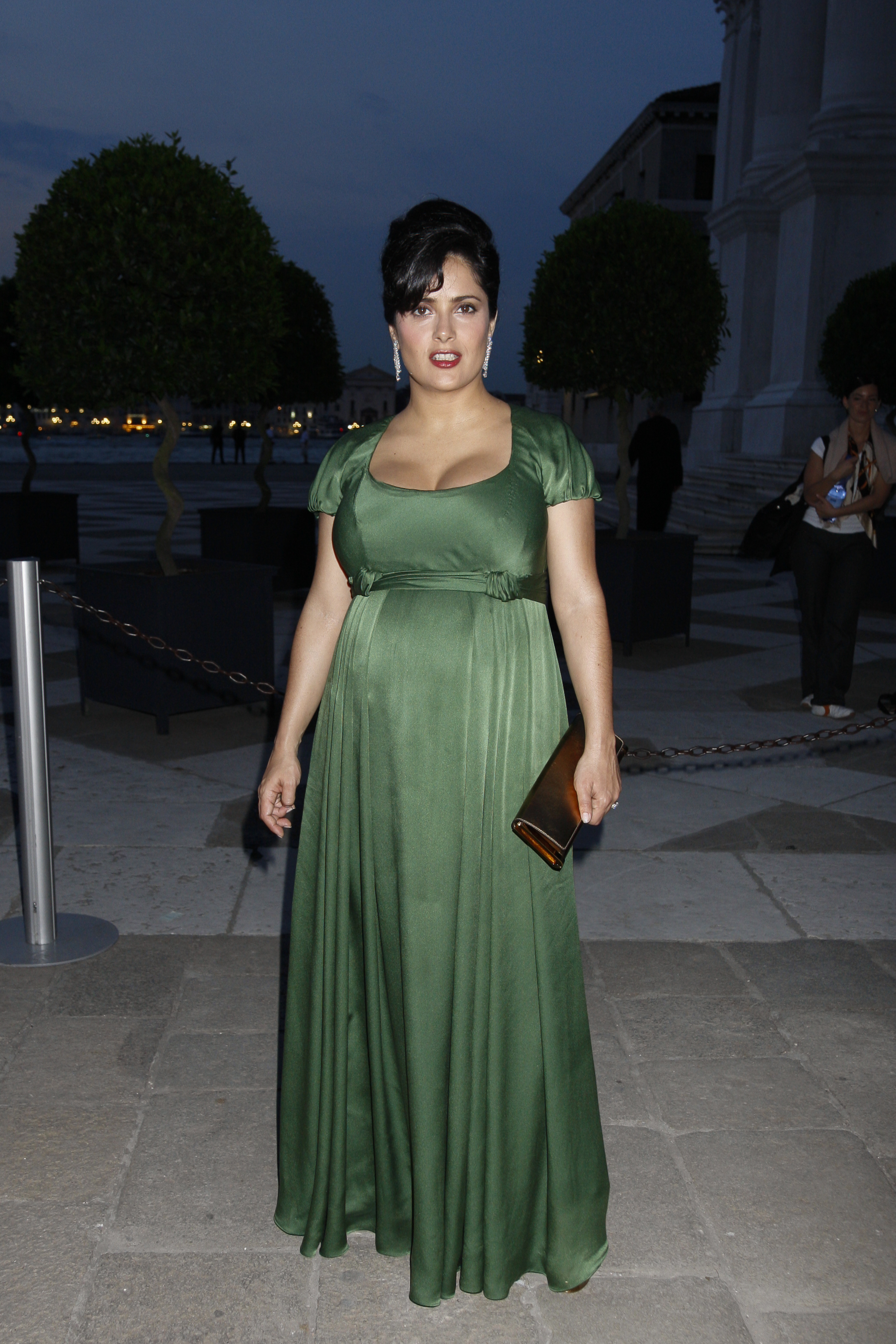 Hayek attended an event in Venice while pregnant, wearing a flowing green gown that highlighted her maternal glow. Her complexion looked radiant with natural warmth, her hair styled in an elegant updo with statement earrings.