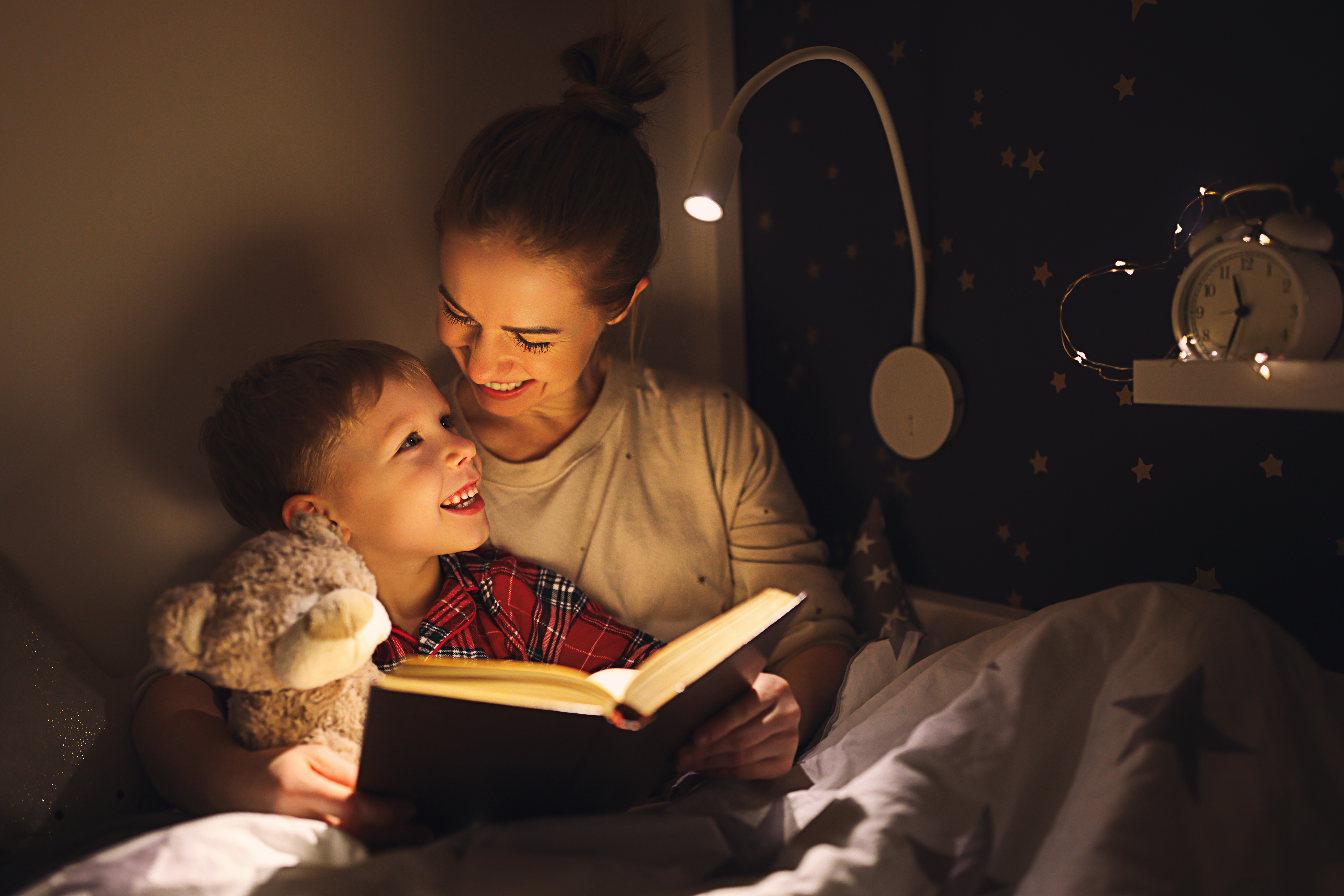 Cheerful mother and son cuddling and reading book | Source: Getty Images