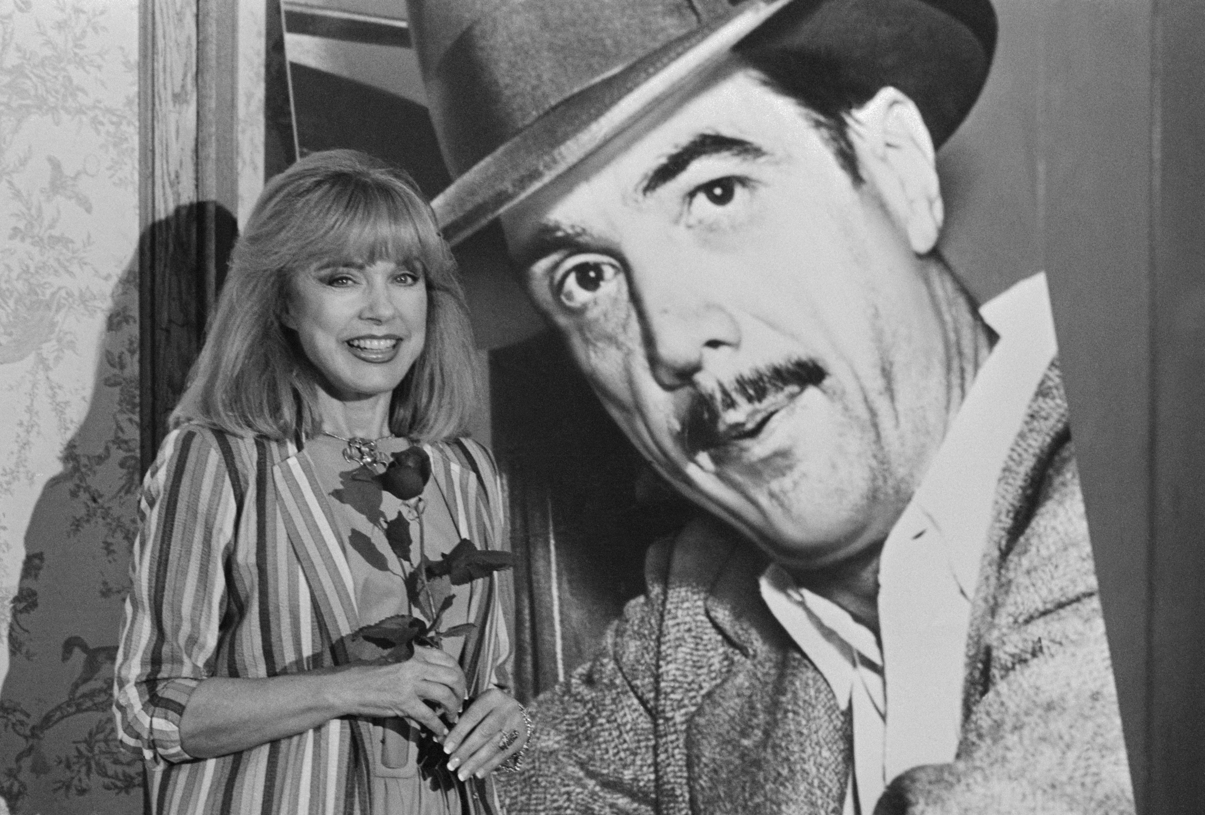 Terry Moore posing next to a poster of Howard Hughes in 1983 | Source: Getty Images