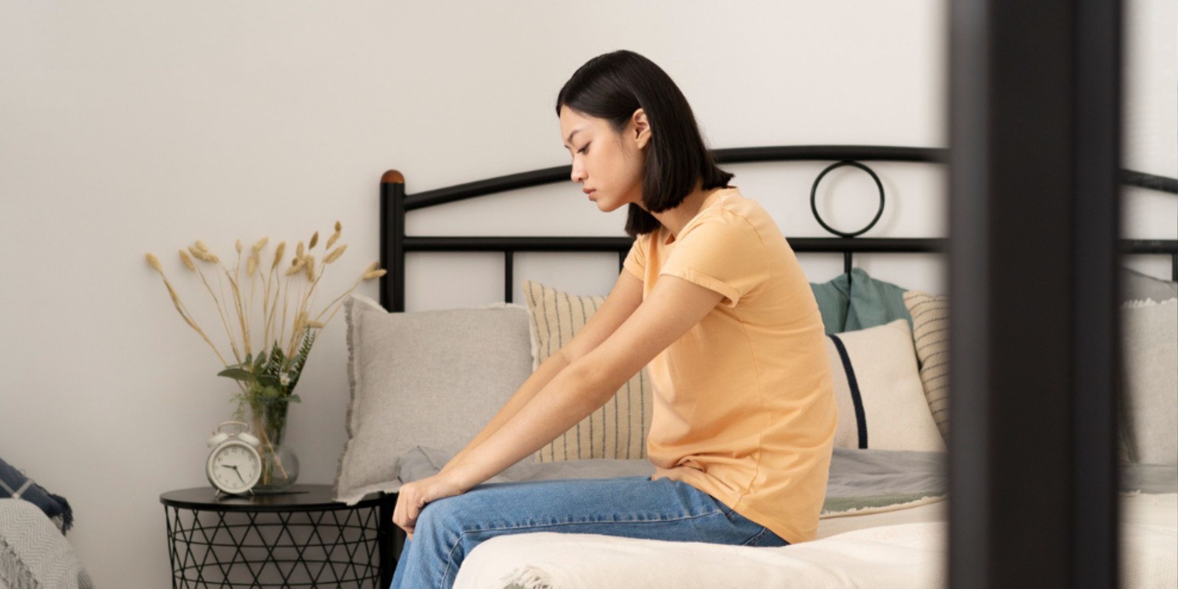 A sad woman sitting on her bed | Source: Freepik