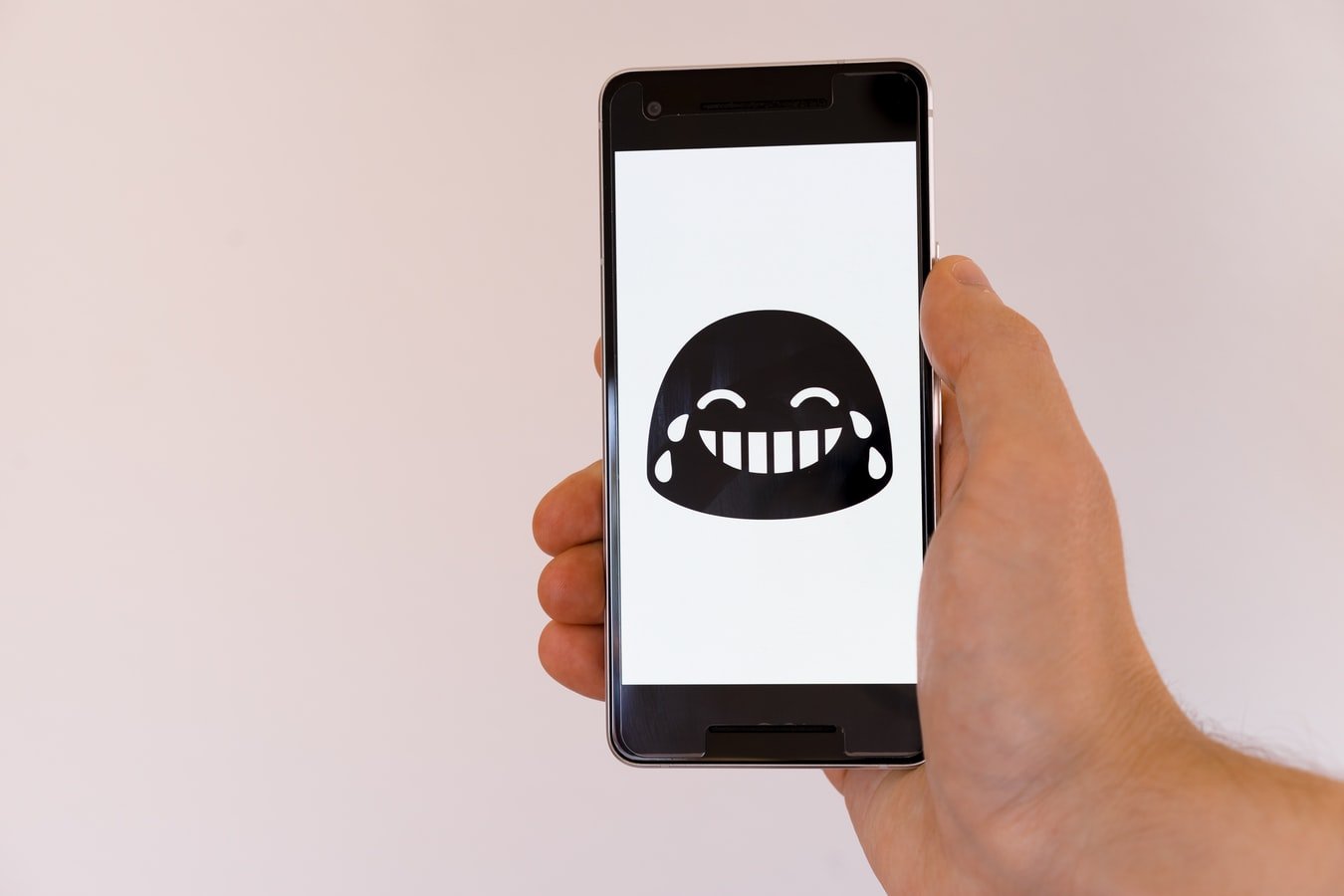 A laughing out loud emoji on a cell phone. | Photo: Unsplash/Markus Winkler