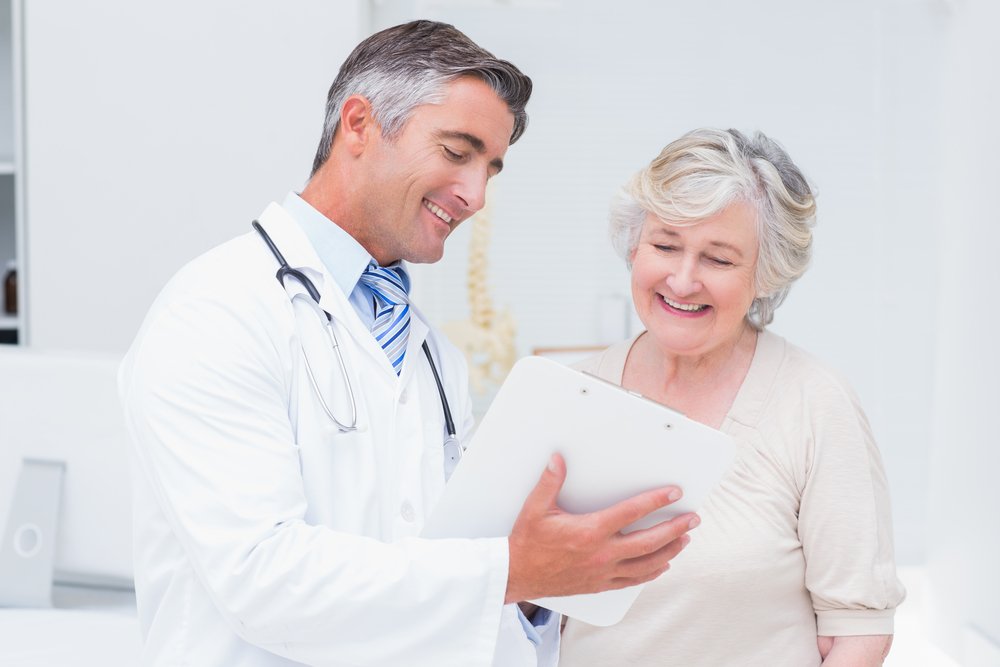 Happy doctor and patient discussing over reports in a clinic | Photo: Shutterstock