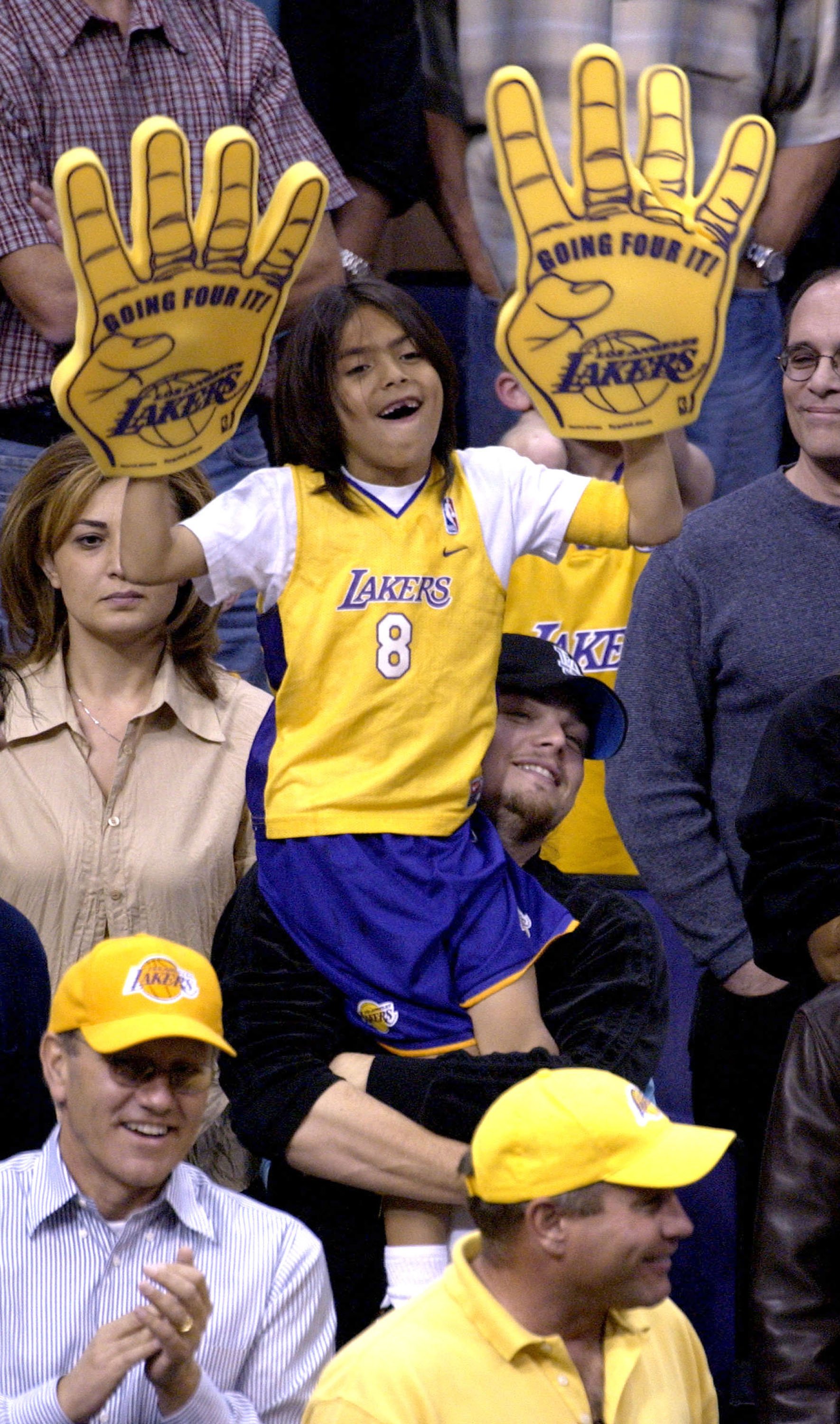 Leonardo DiCaprio holds up an unidentified child as they attend the Lakers v Timberwolves in Los Angeles | Source: Getty Images