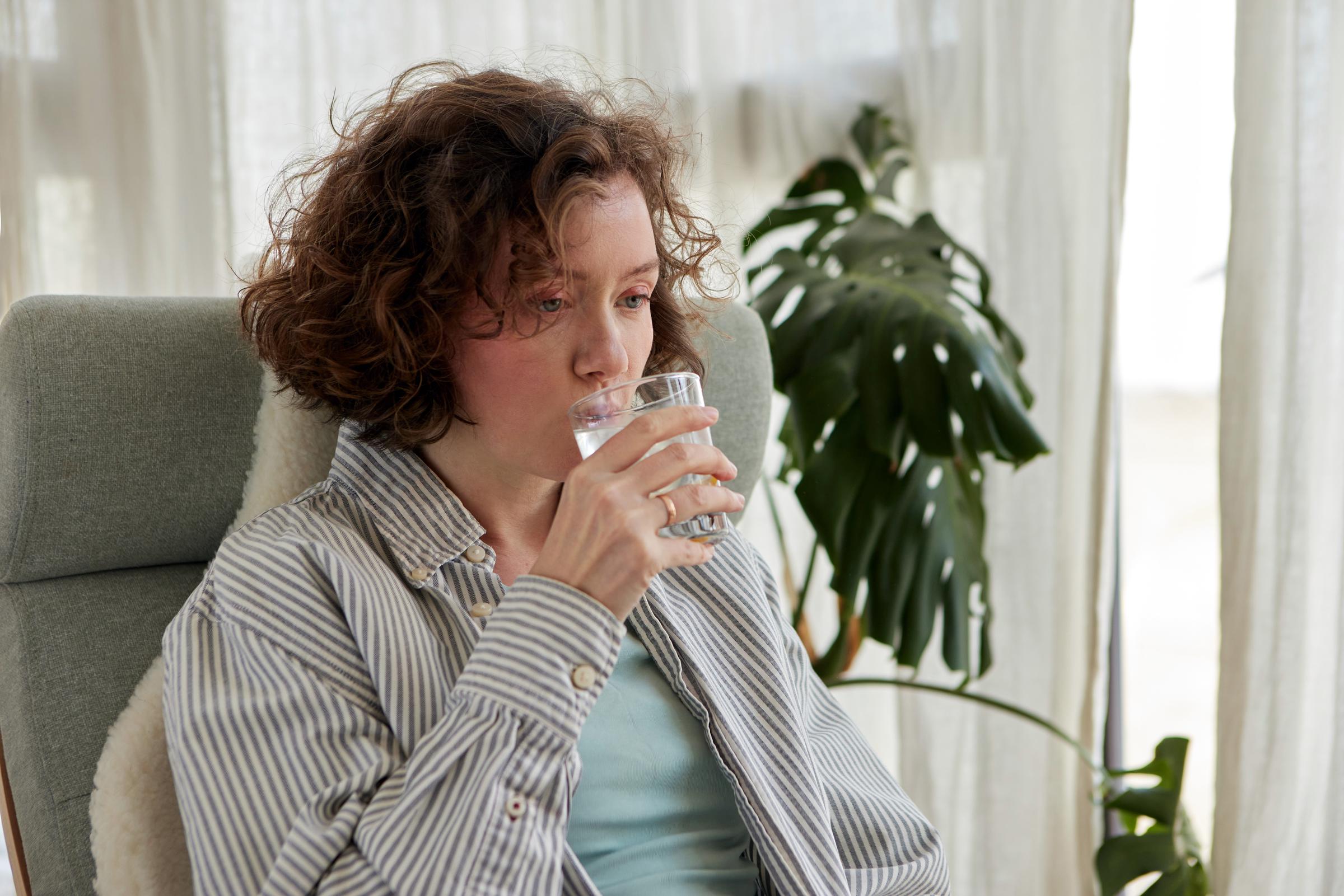 A woman drinking water to help ease hiccups | Source: Getty Images