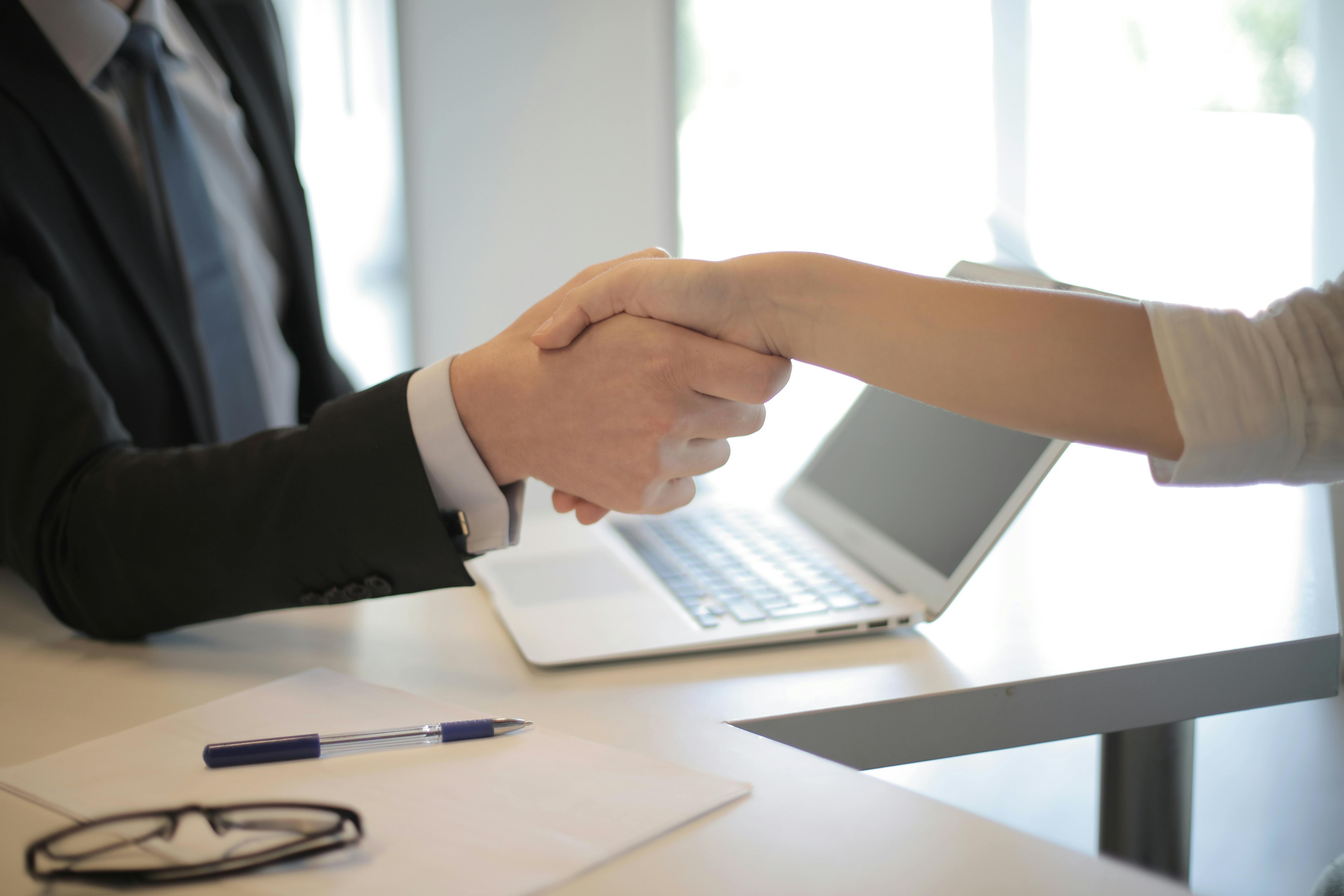 A man and woman shaking hands in an office | Source: Pexels