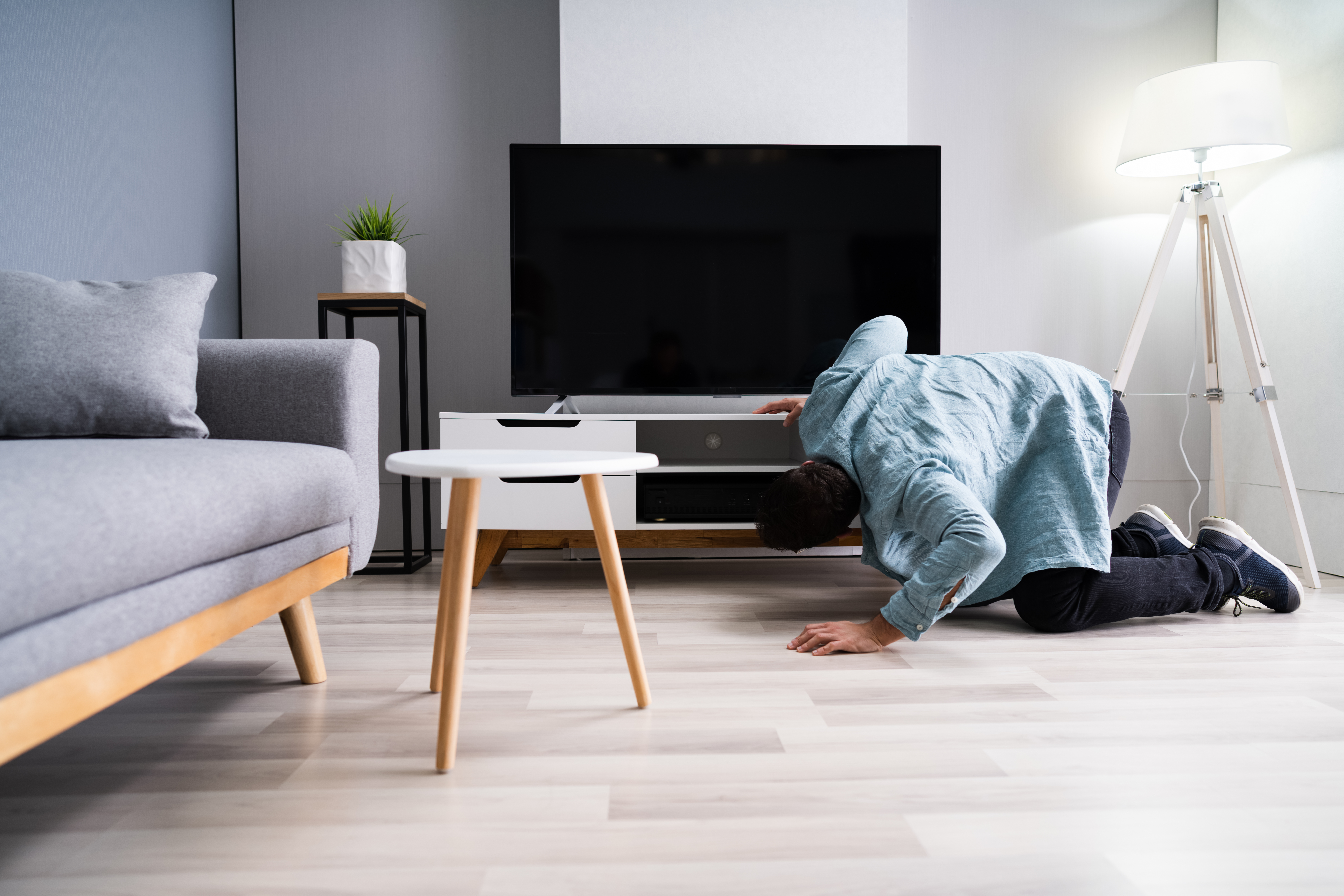 Man is looking for lost things under the sofa and table | Source: Shutterstock.com