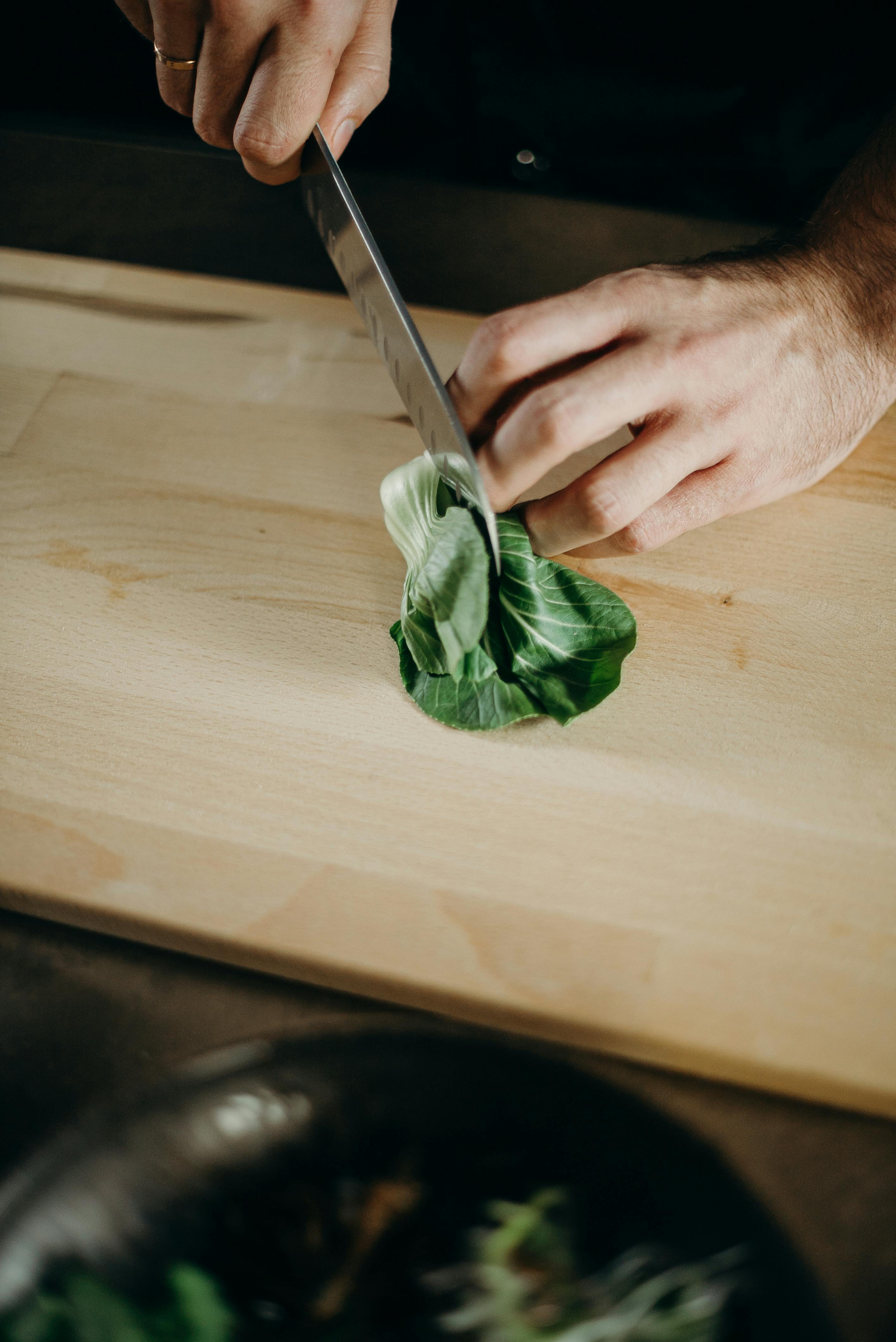 A person slicing a piece of bok choy | Source: Pexels