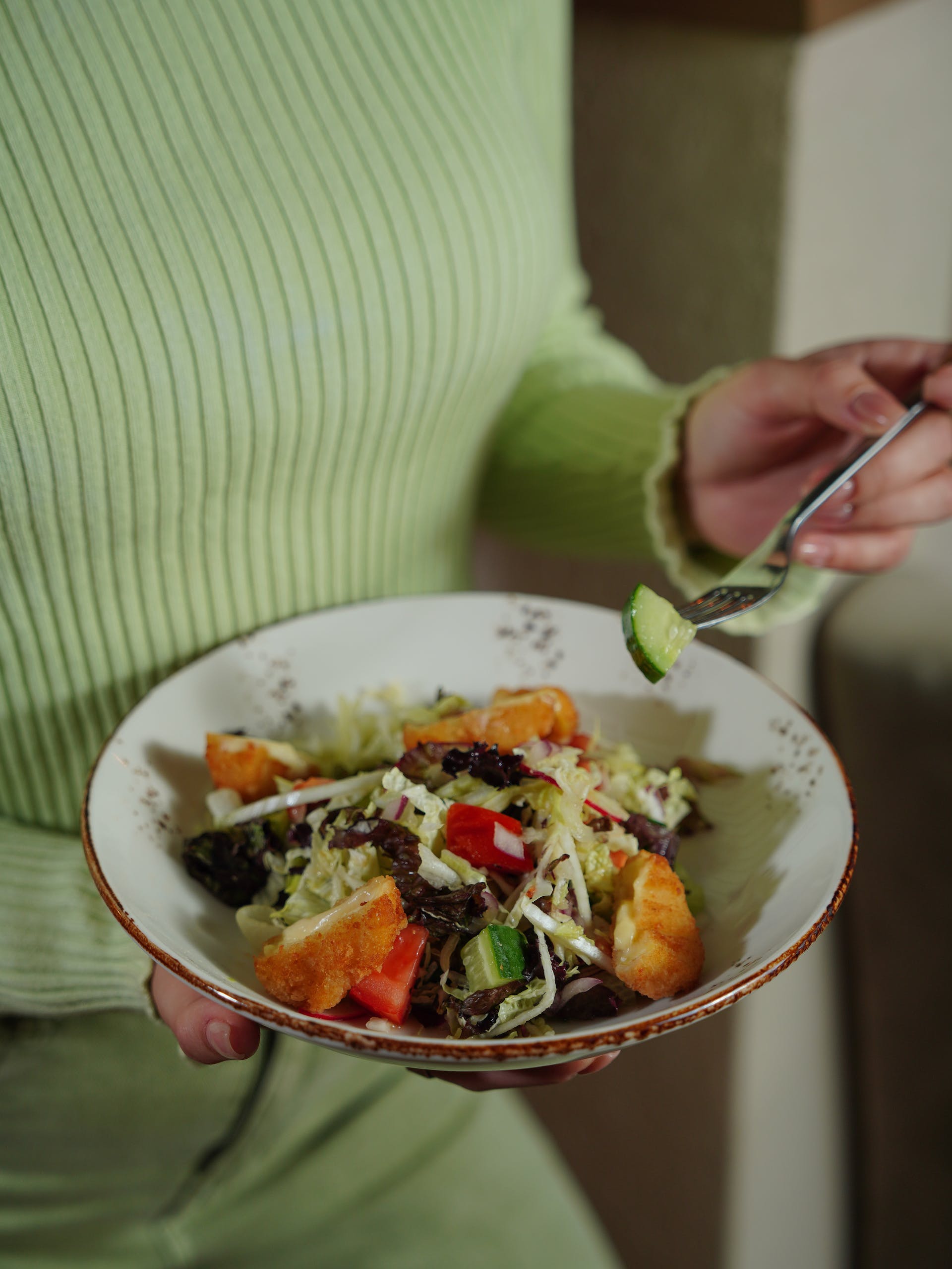 Close up of a woman holding a salad bowl | Source: Pexels