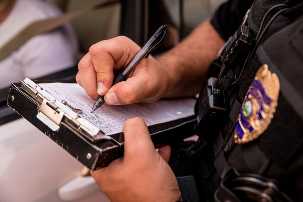 Ein Foto eines Polizeibeamten, der einen Strafzettel ausstellt. | Quelle: Shutterstock
