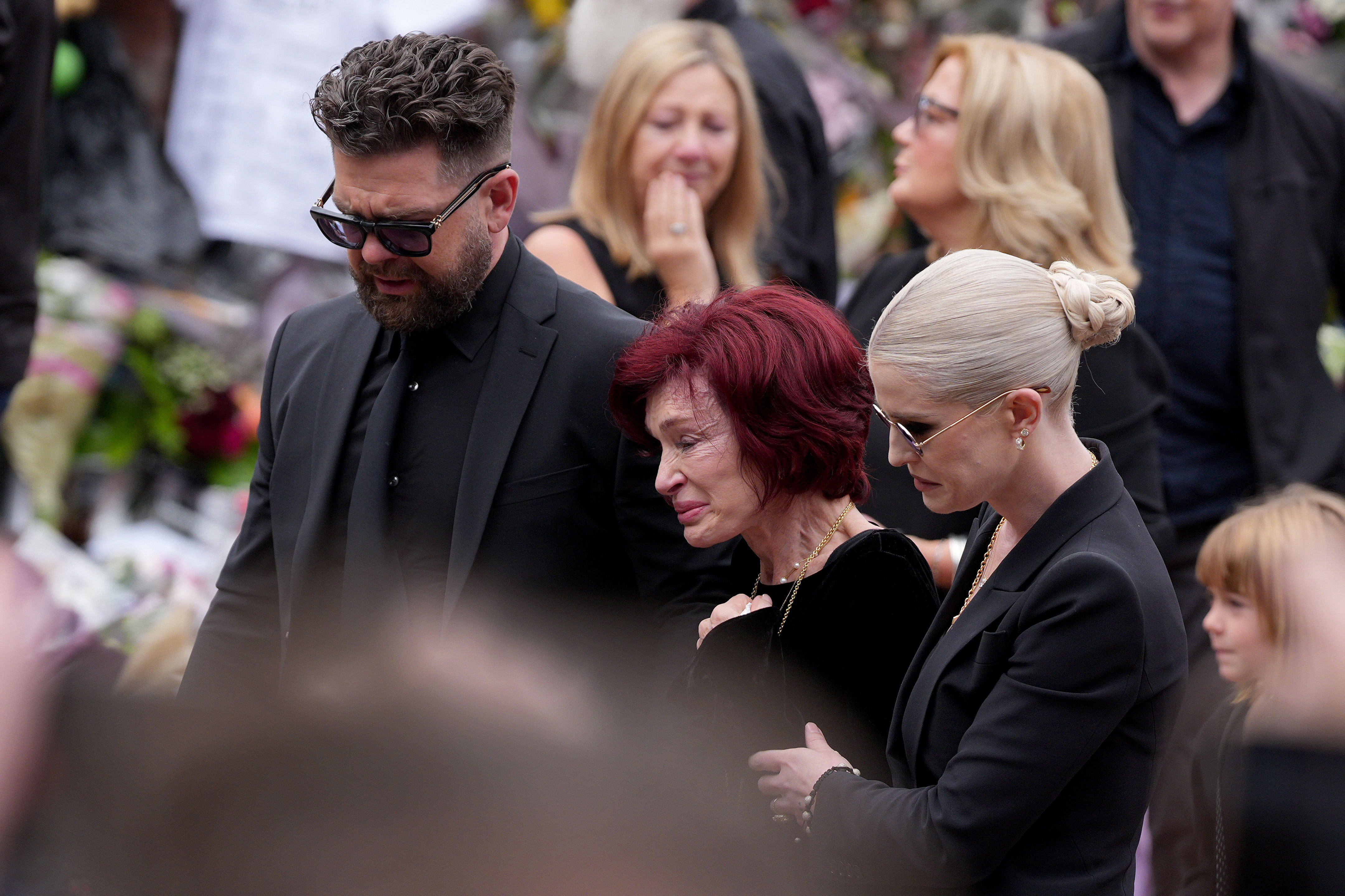 Jack, Sharon, and Kelly Osbourne viewing tributes to the late Ozzy Osbourne from fans at Black Sabbath Bench and Bridge on July 30, 2025, in Birmingham, England. | Source: Getty Images
