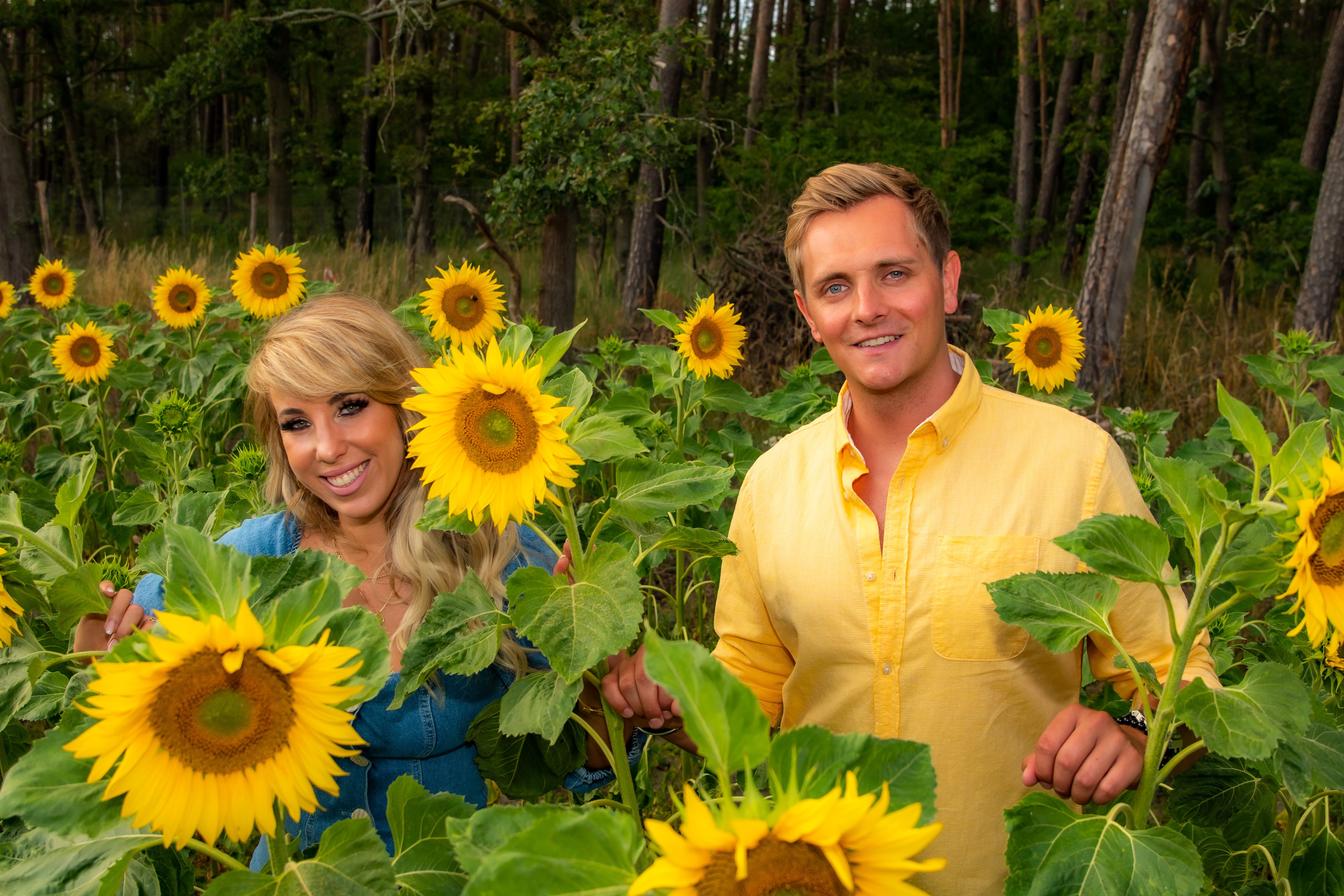 Annemarie Eilfeld und ihr Freund Tim Sandt stehen während der Dreharbeiten in der Nähe von Dresden auf einem Feld blühender Sonnenblumen. | Quelle: Getty Images
