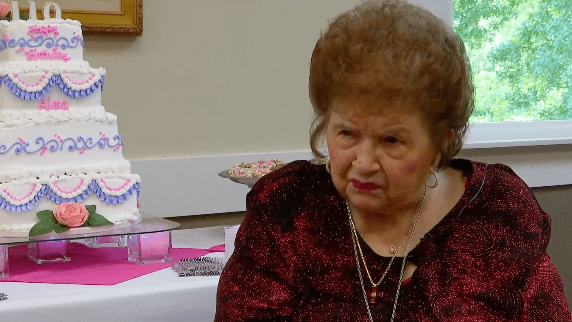 110-year-old Alma Kahl dressed in red and sitting next to her birthday cake. | Source: WOWK 13 News